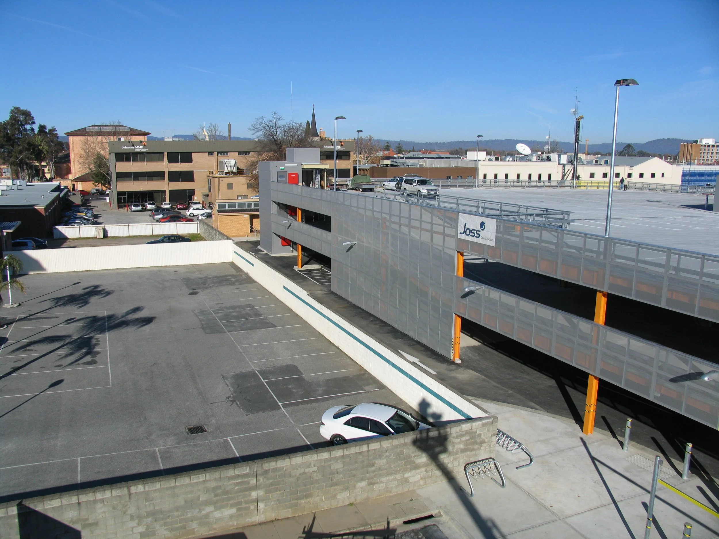 View of a parking garage with cars parked and a cityscape in the background.