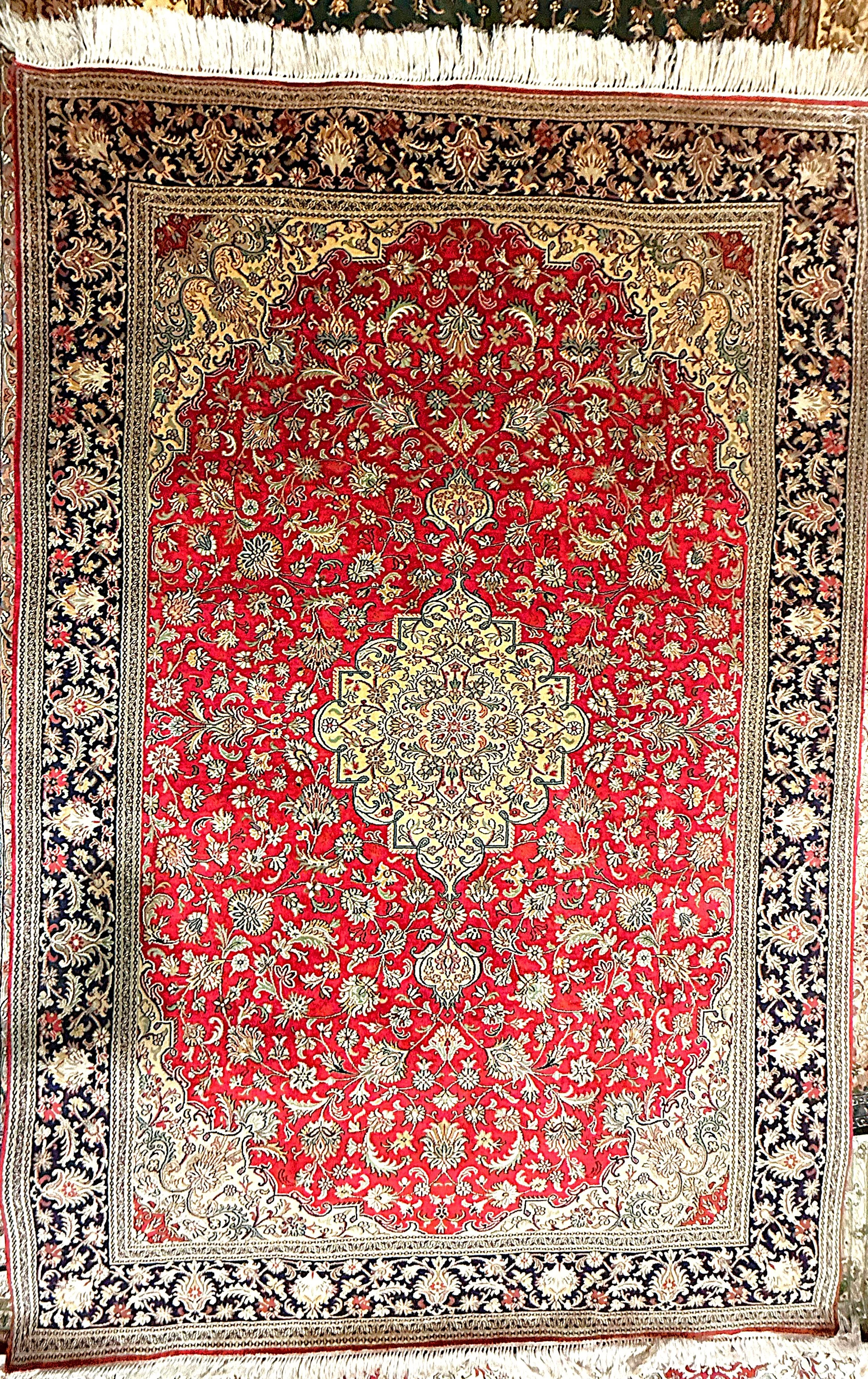 A traditional Persian-style rug with a central beige medallion, intricate floral and vine patterns, a red background, and a black and beige border with floral motifs.