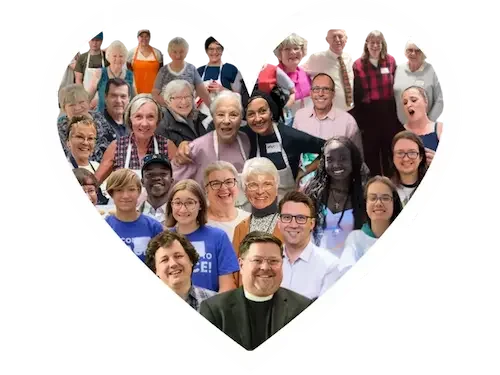A diverse group of people forming a large heart shape, smiling for the camera.