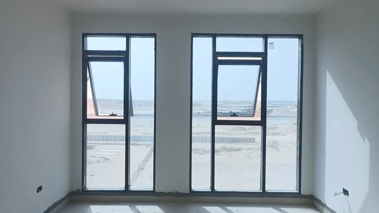 Unfinished room with three large standard glass windows showing an outdoor desert landscape. Residences Oman Duqm