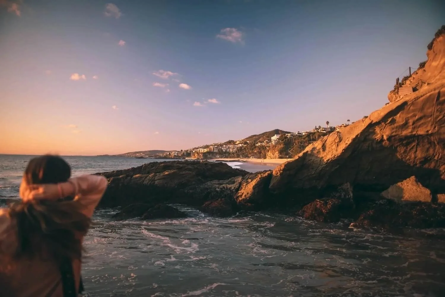 Person overlooking the rocky coastline at sunset in Laguna Beach, California