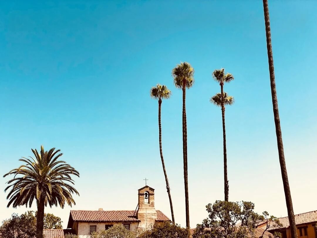 Palm trees and historic Mission San Juan Capistrano beneath a clear blue sky