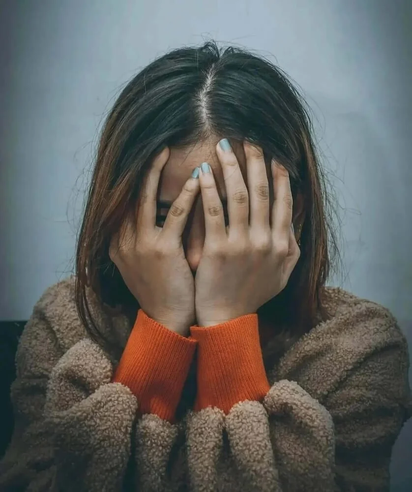 Woman covering her face in distress, representing 7-OH kratom withdrawal and the need for detox