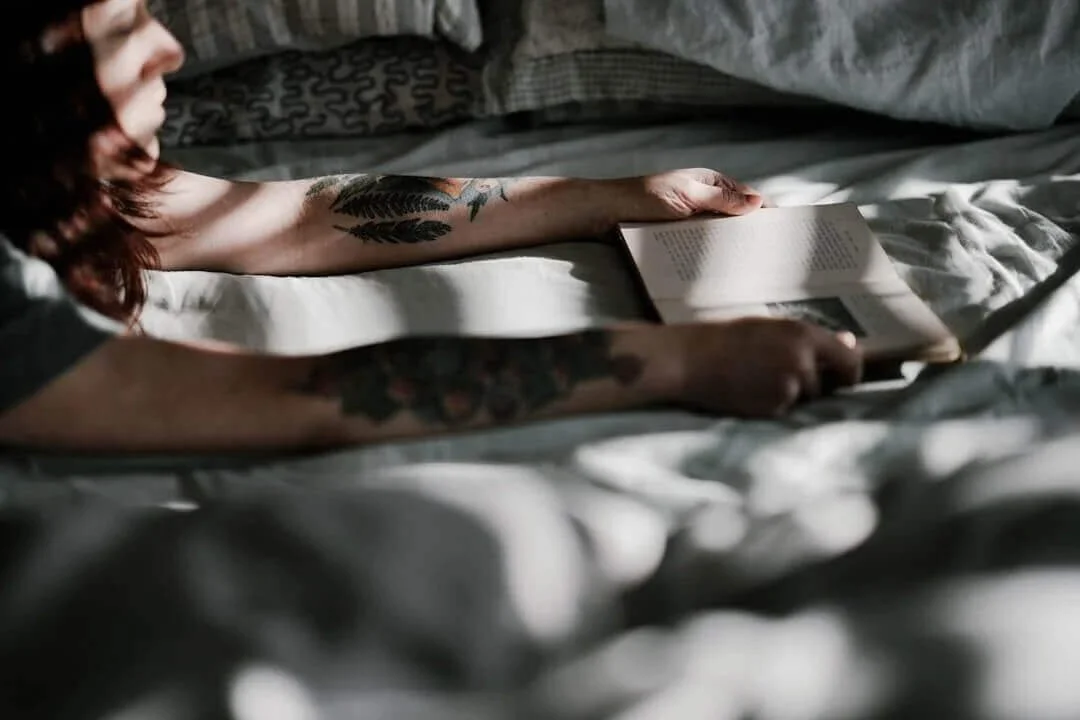 Person resting in bed with a book, representing recovery during oxycodone detox