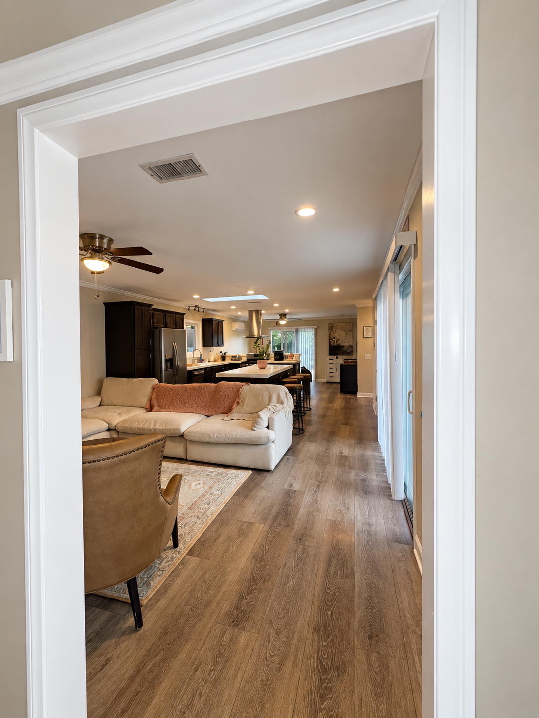 Living room with a sectional sofa opening onto the kitchen and dining area at Salterra OC Detox & Treatment.