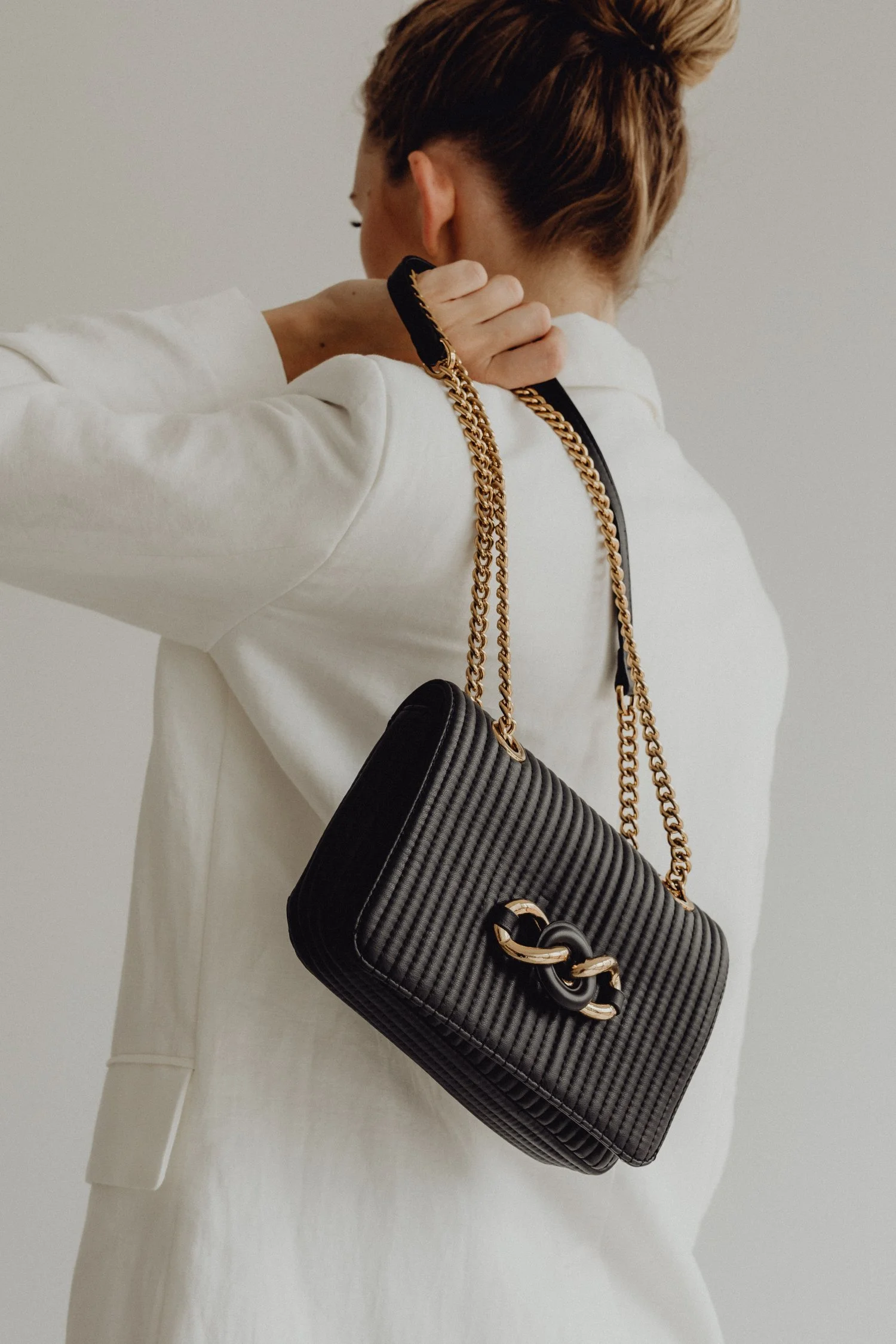 Premium Squarespace Template, Coaching Squarespace Template, Avelã Creative. Woman in white blazer holding black quilted handbag with gold chain strap.