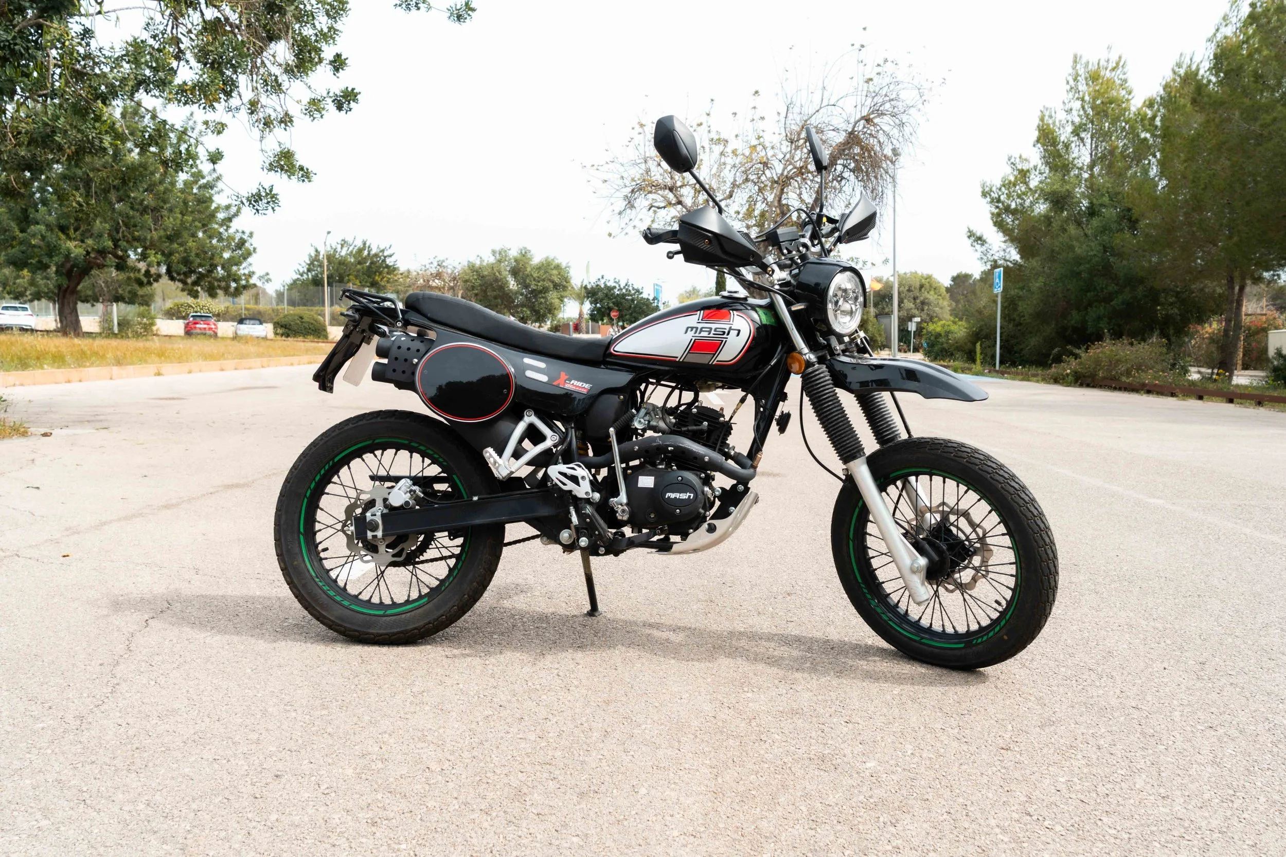 Motocicleta negra y blanca estacionada en un espacio abierto con árboles y cielo despejado.