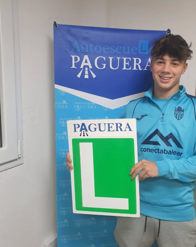 Joven sonriente sosteniendo un cartel con la letra L en color verde y la palabra Pagura en la parte superior, en un entorno de academia de manejo llamada Autoescuela Pagura.