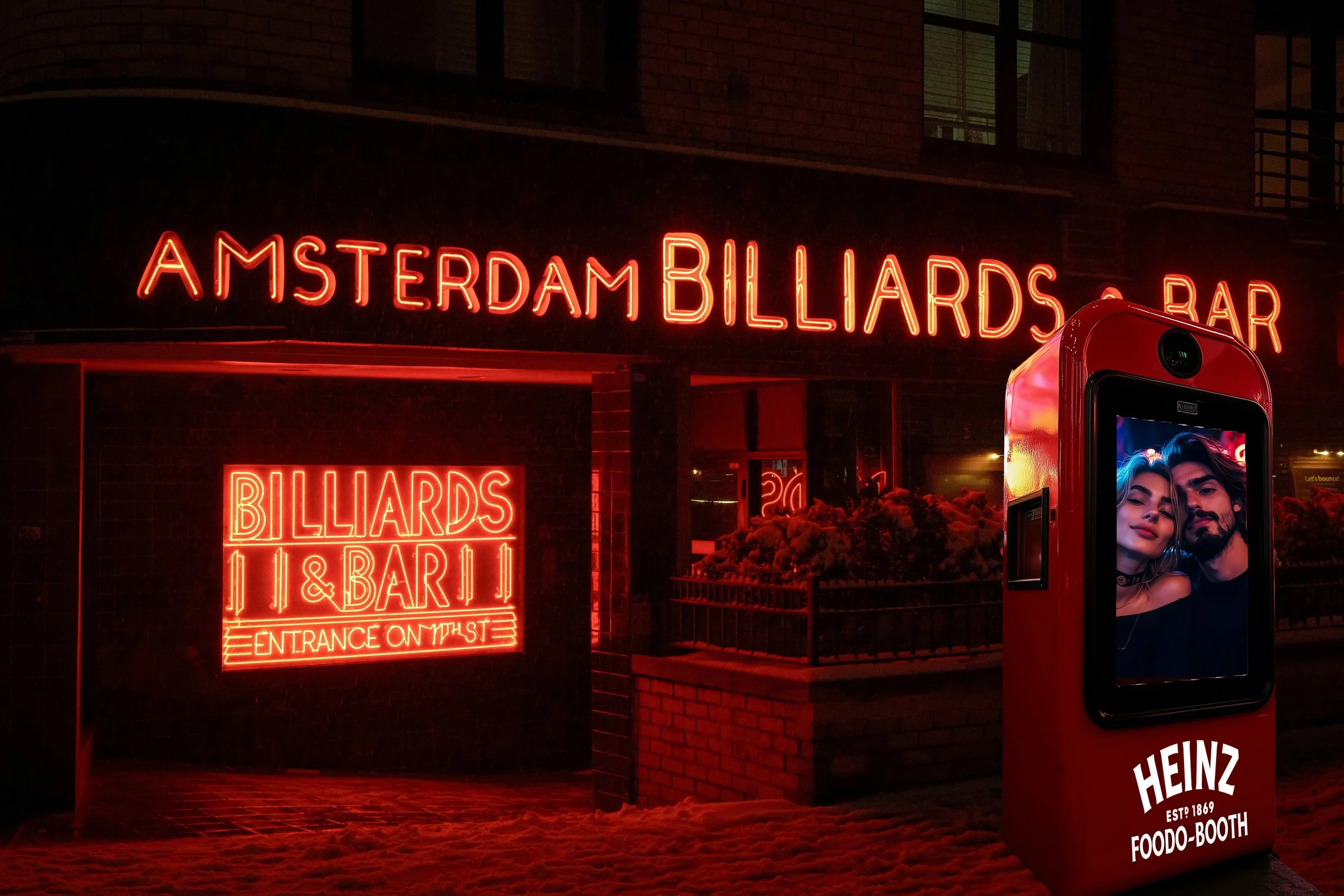 A neon sign reads 'AMSTERDAM BILLIARDS BAR' in front of a building. There is another neon sign near the entrance that says 'BILLIARDS & BAR' with smaller letters 'ENTRANCE ON 1ST' underneath. In the foreground, a red Heinz-branded photo booth displays a picture of a couple.