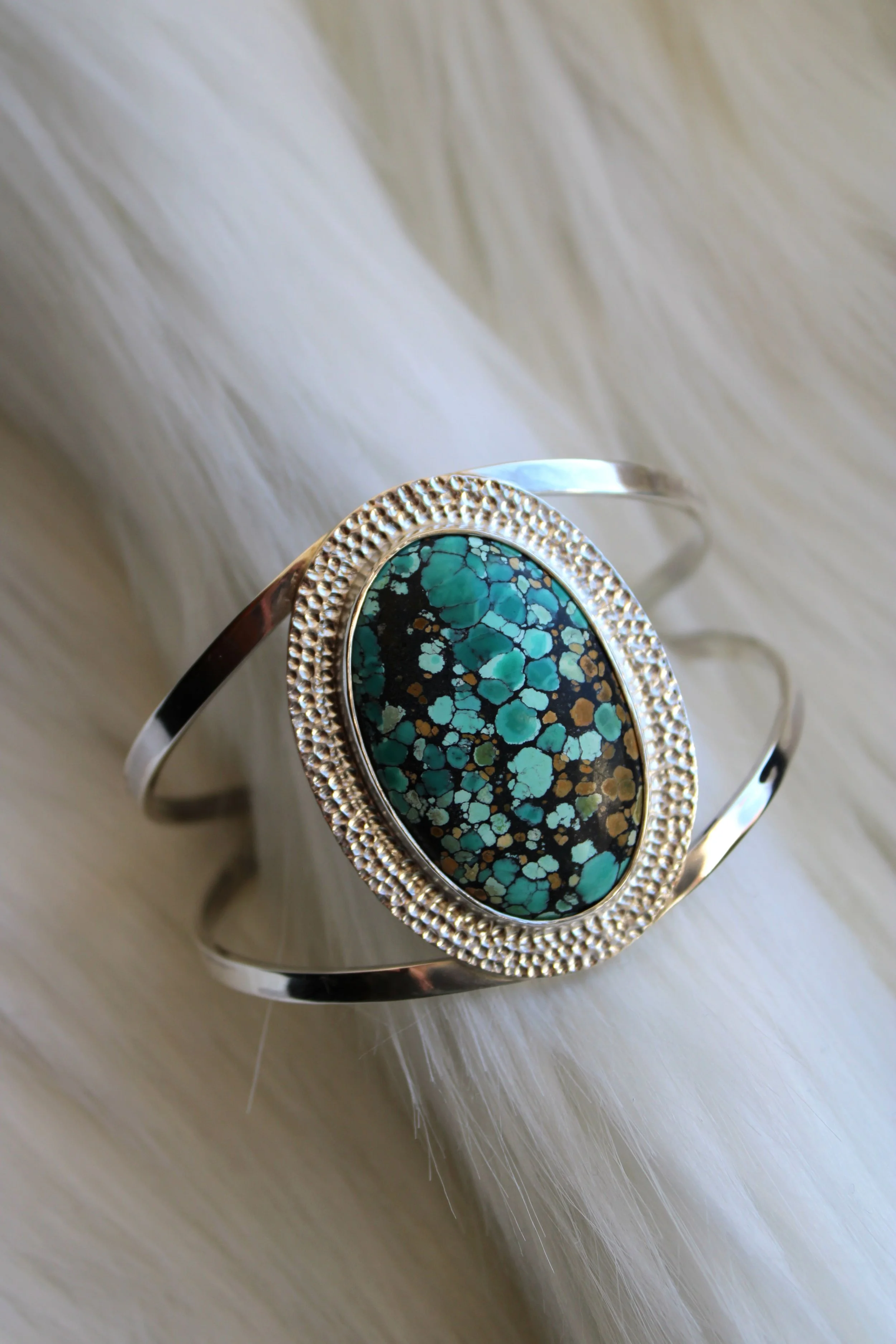 Bracelet double anneau avec une pierre turquoise et marron, posé sur un fond blanc.