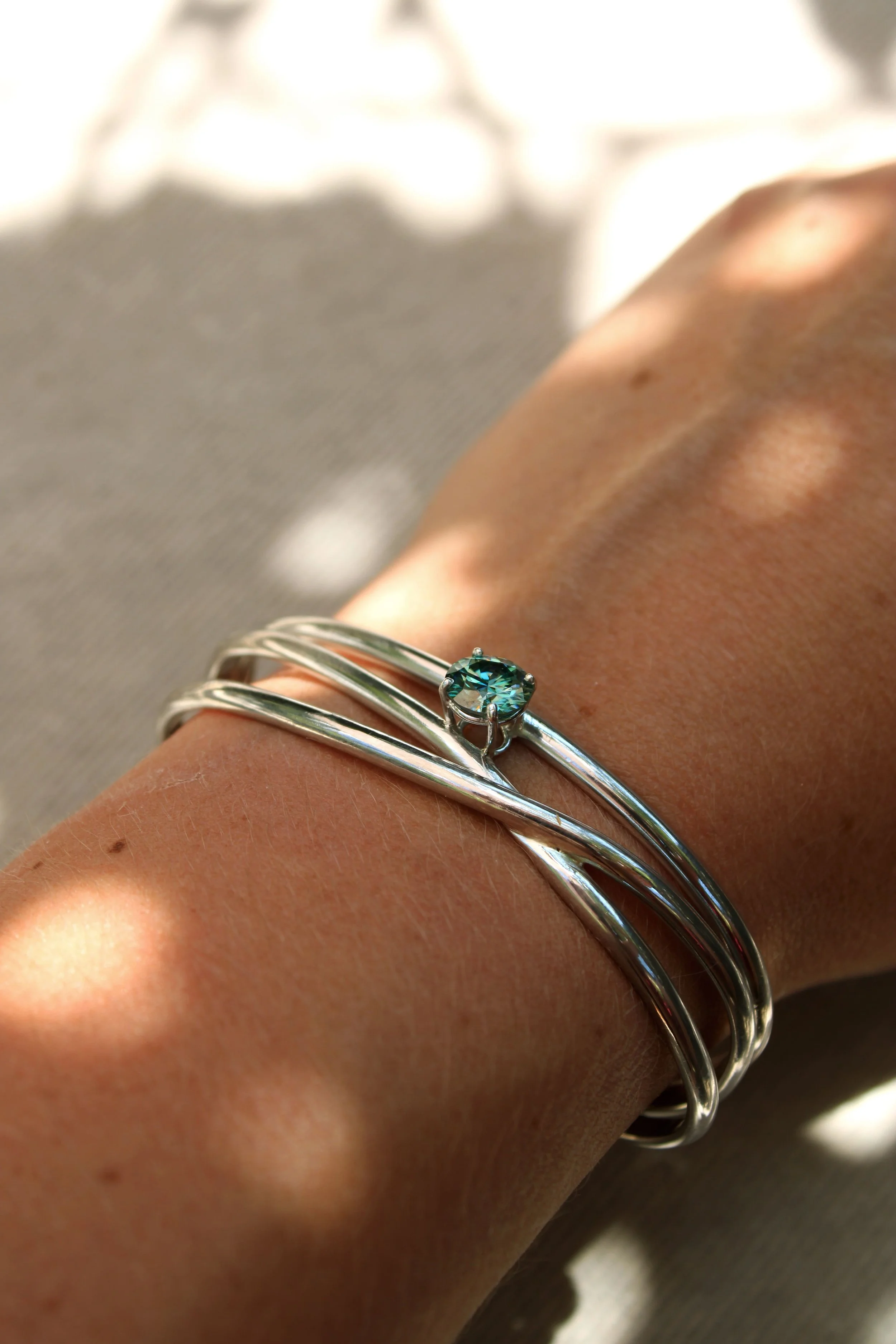 Bracelet en argent avec une pierre précieuse bleue sur un poignet.