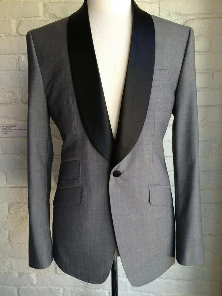 Gray blazer with black satin lapel displayed on a mannequin in front of a white brick wall.
