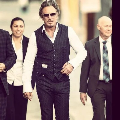 A man with sunglasses walking with two women and a man in an outdoor setting.