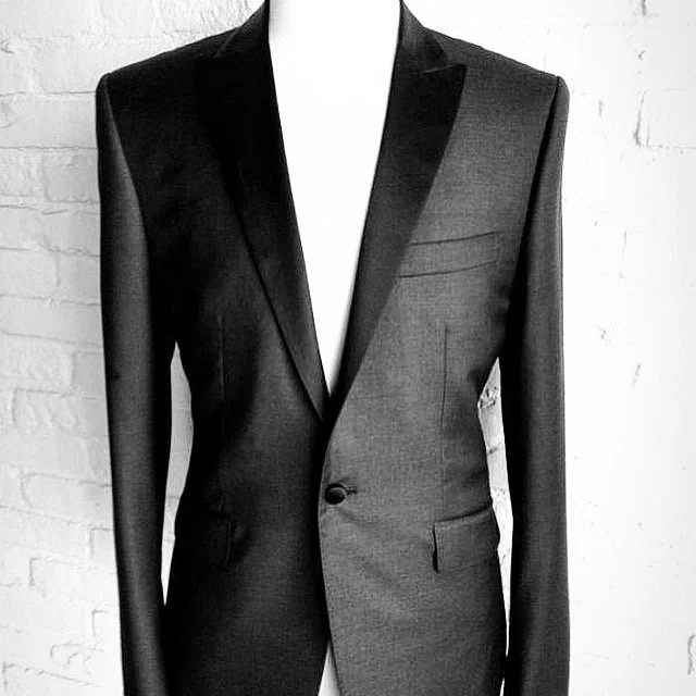Black and gray men's tailored blazer on a white mannequin against a white brick wall.