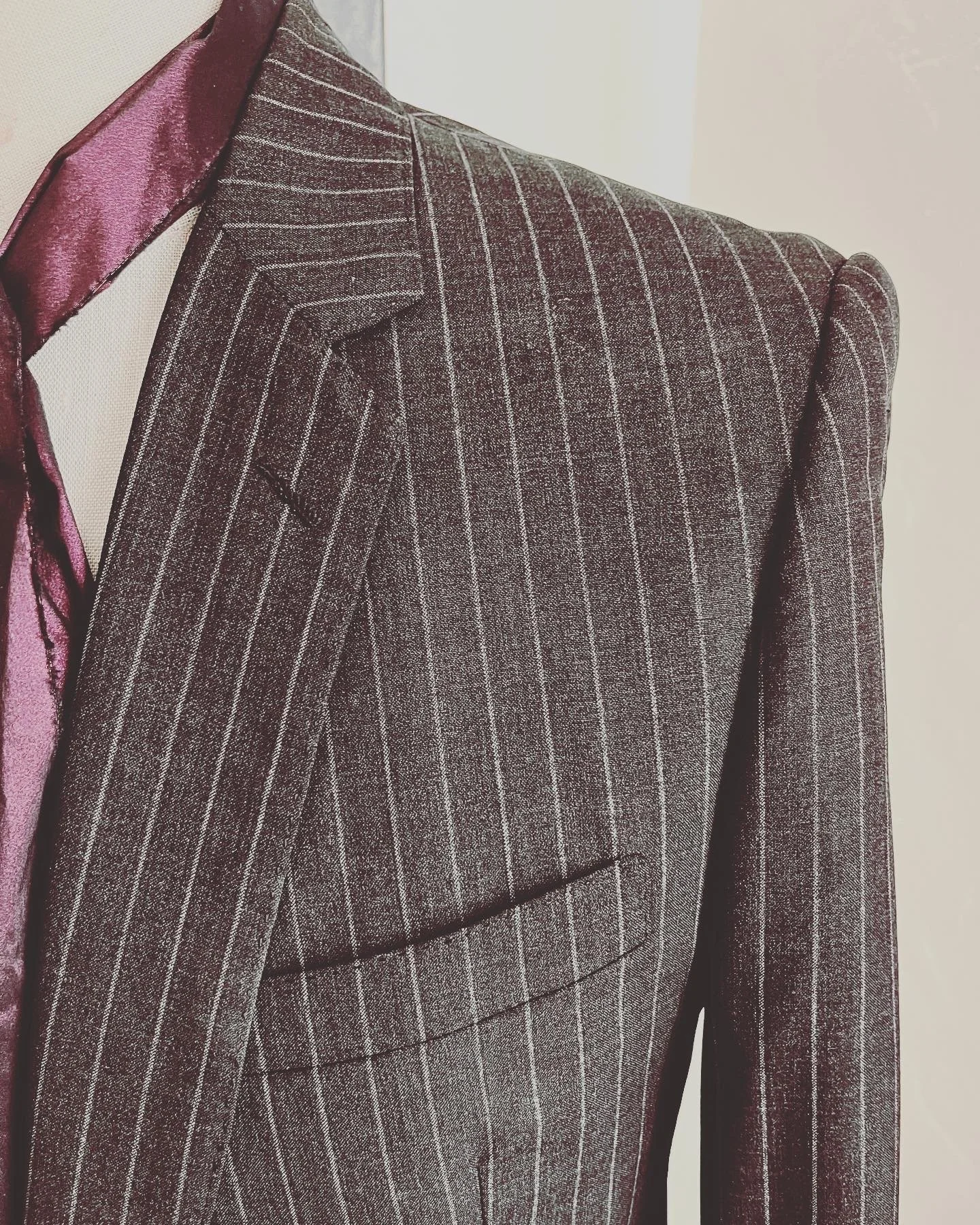 Close-up of a pinstripe suit jacket with a satin tie on a mannequin.