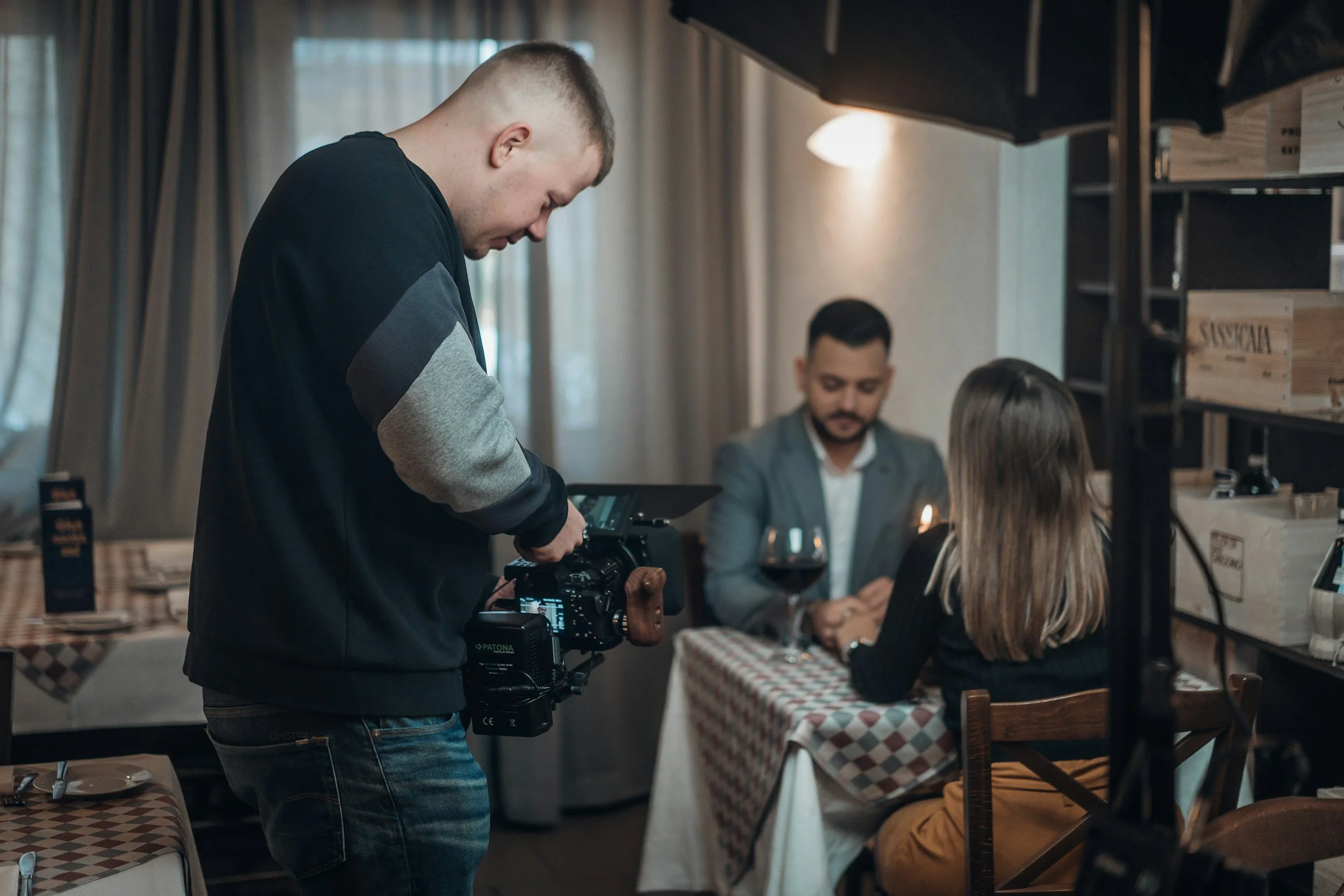 Un homme filme un couple lors d'une séance de photos dans un restaurant.