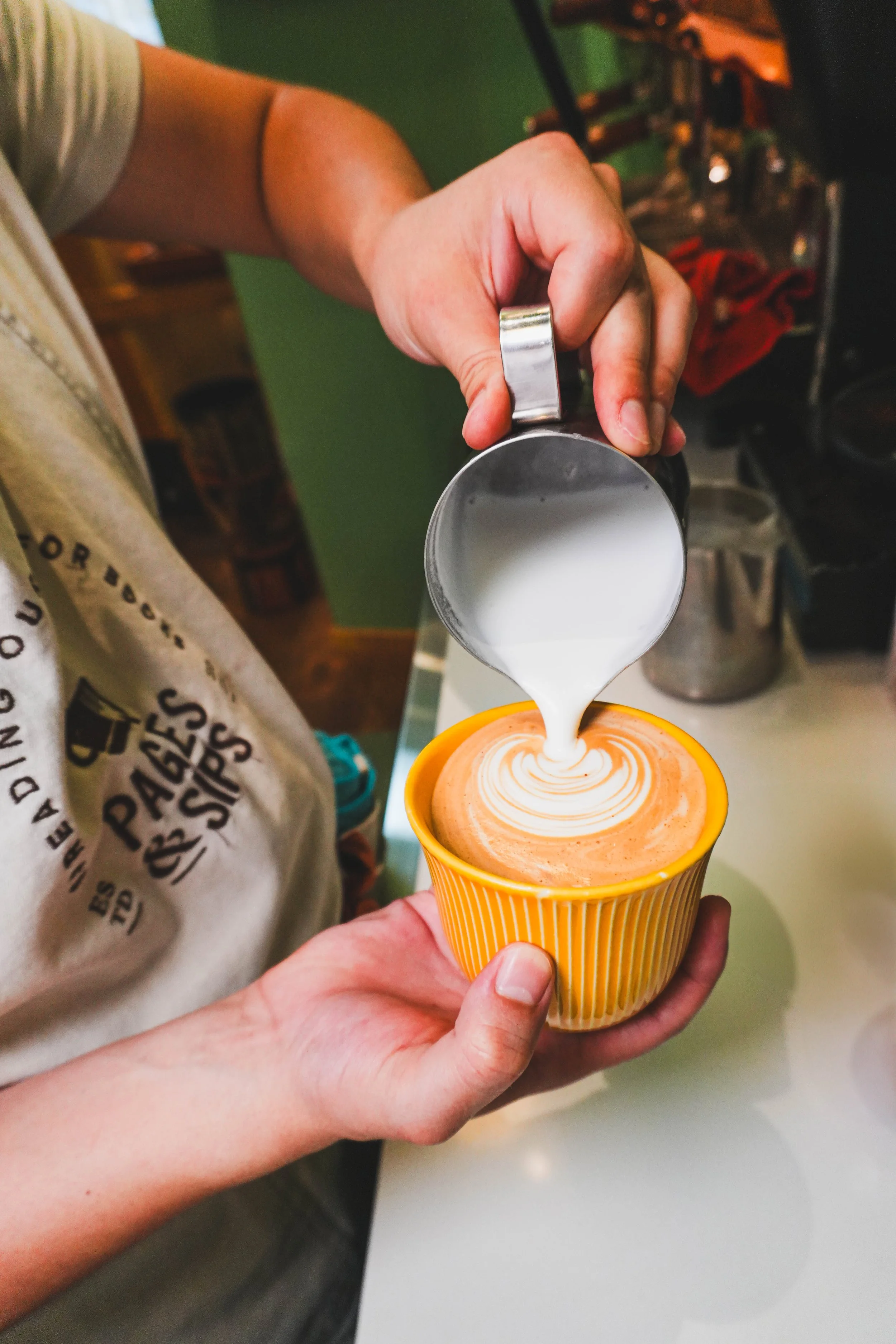 Photo prise par Dreamer's Table avec un Barista en train de préparer un latte chez Pages & Sips à Genève