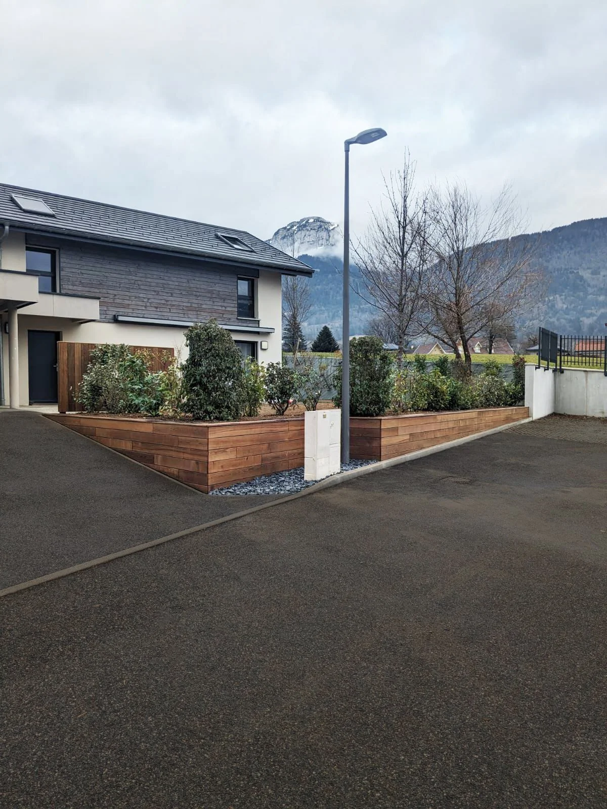 Clôture de maison moderne en bois et végétations ainsi qu'un terrassement de jardin.