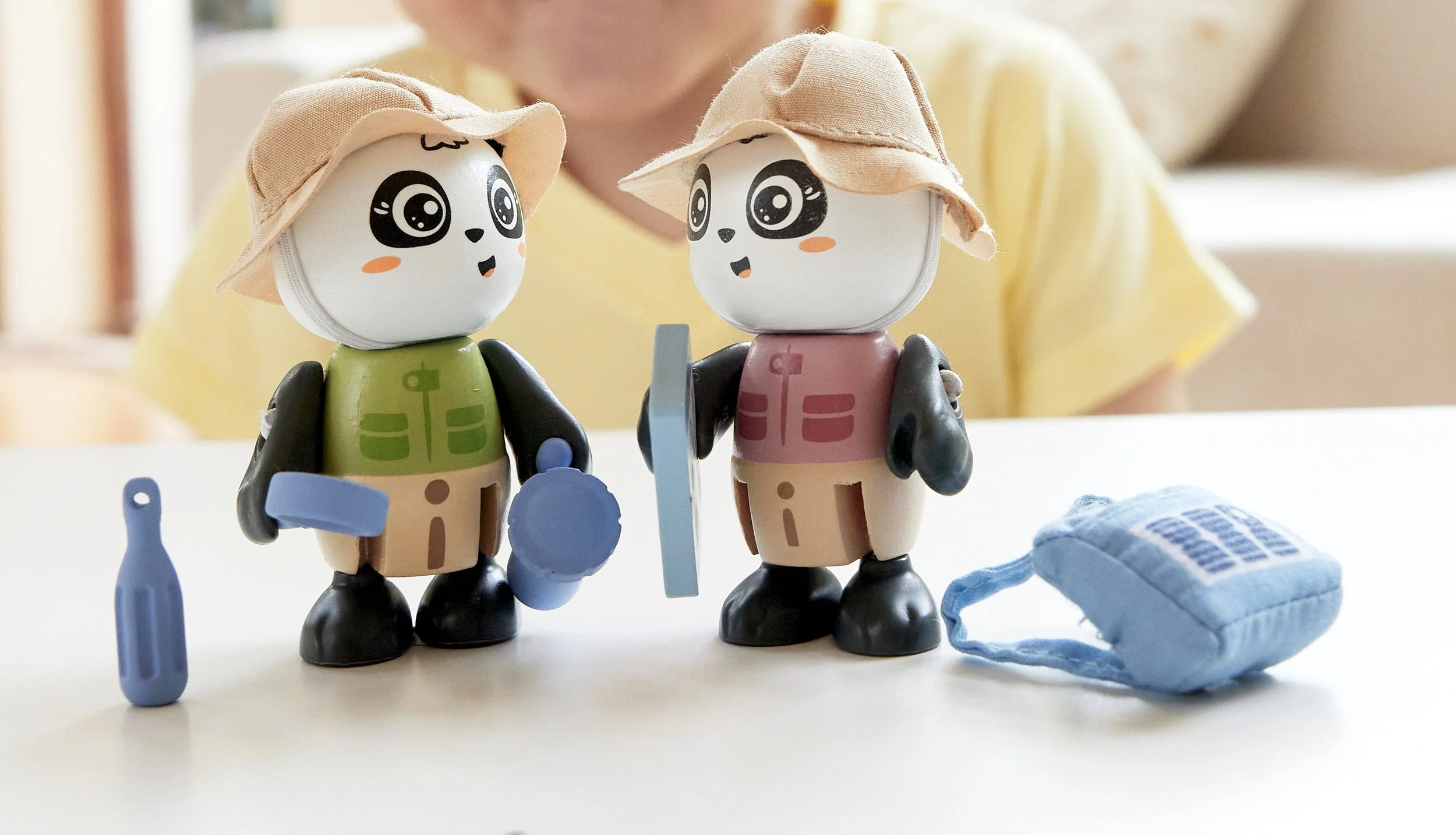 Two Green Planet Explorers charachters by Hape, toy figures dressed as nature explorers with hats, backpack, bottle, magnifier glass, torch, and tablet with map