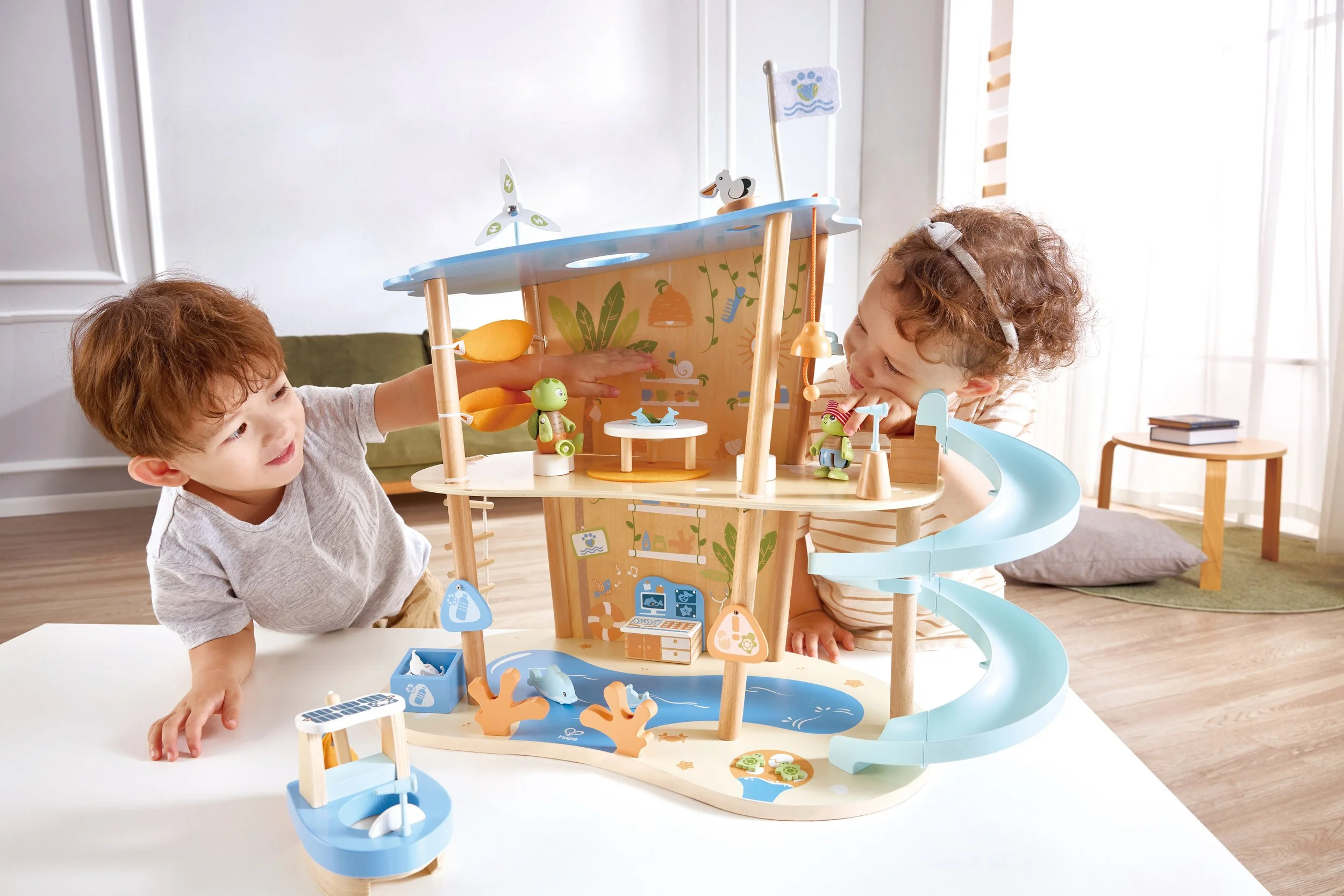 Two children playing with the Green Planet Explorers Ocean Rescue playset by Hape, on a white table in a bright room.