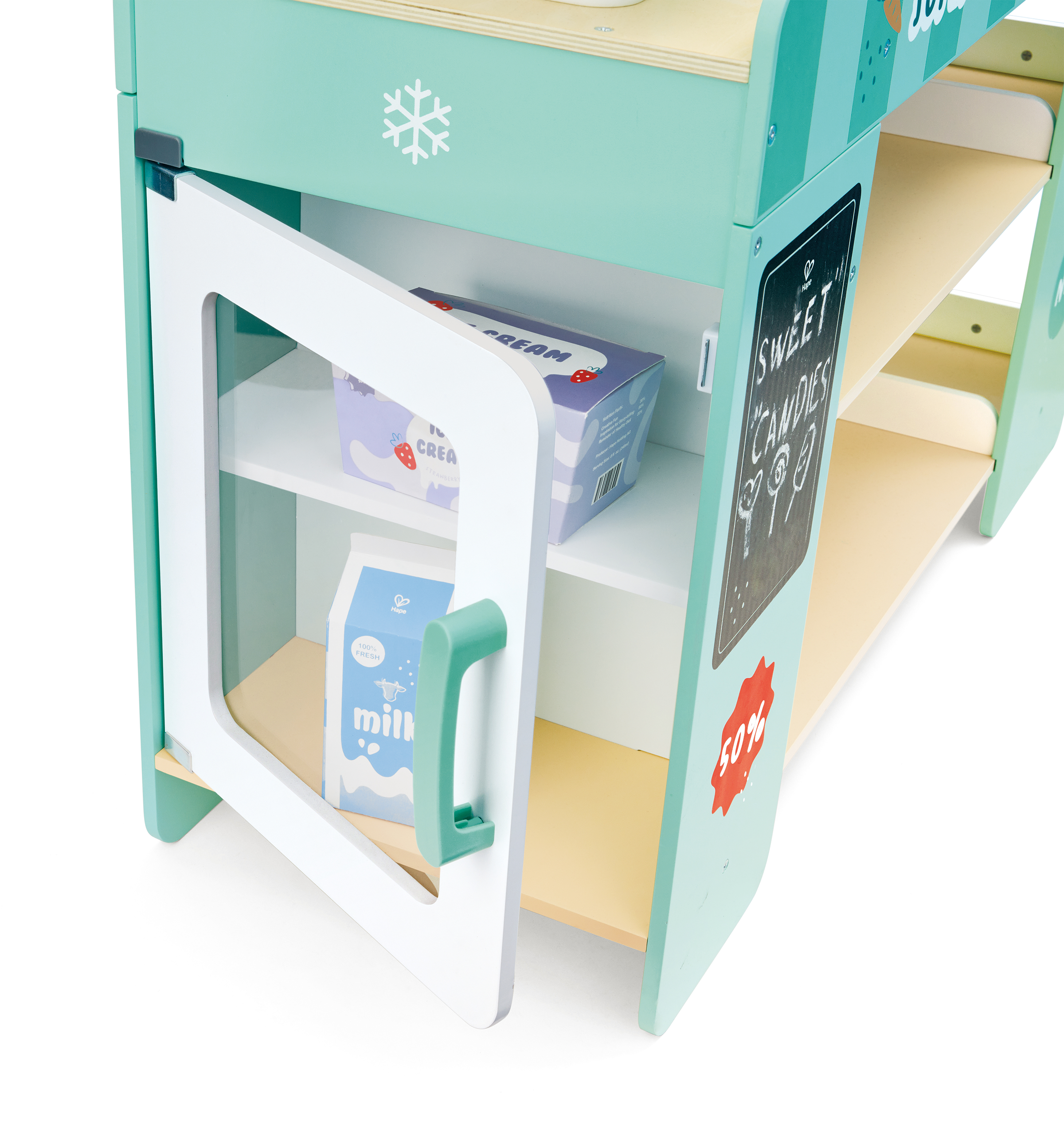 A children's play store with a pastel teal color, featuring a small fridge with a mini milk carton inside and chalkboard signs advertising discounts, surrounded by shelves.