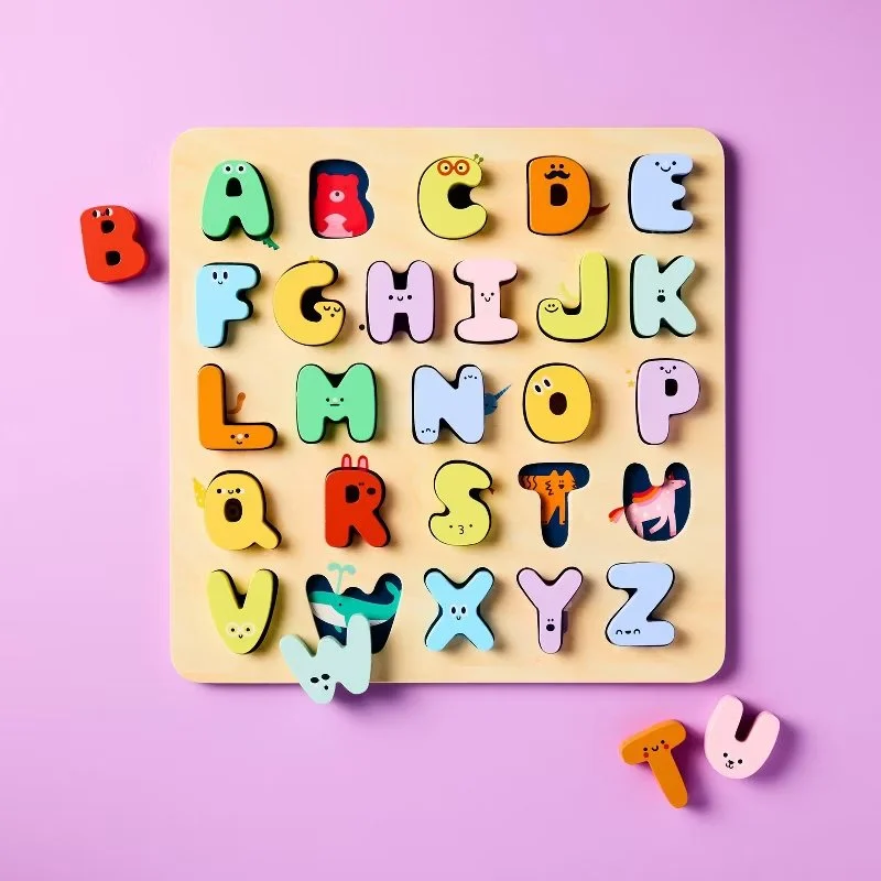 Colorful alphabet puzzle with animal or character designs on a wooden board, set against a pink background. Developed for Target.