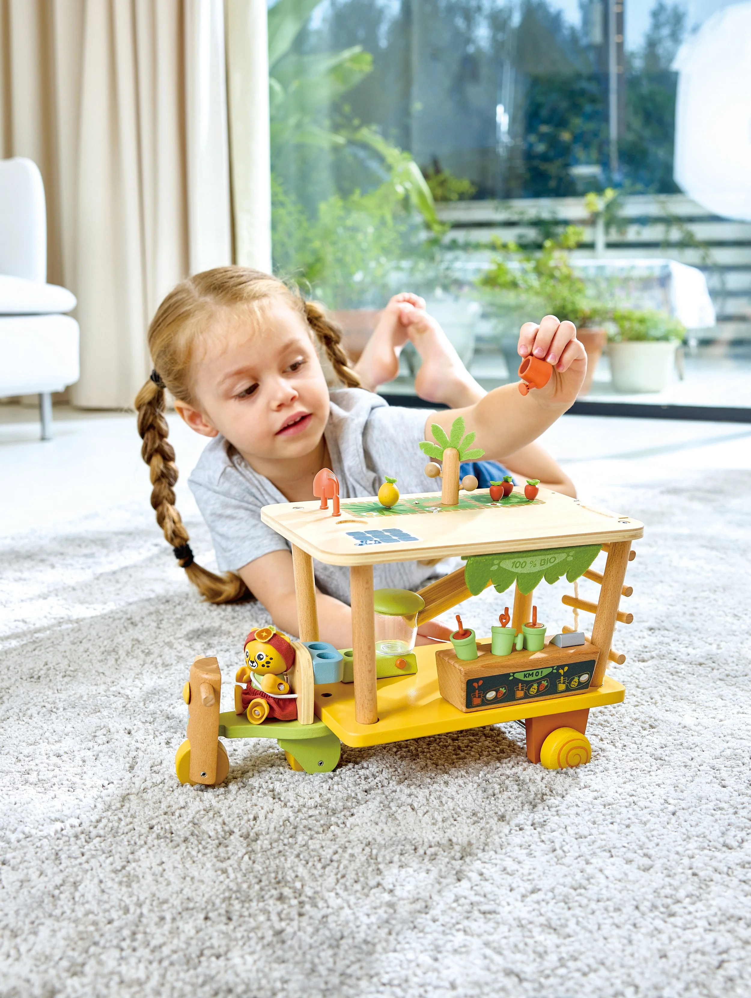 A young girl playing Green Planet Explorer Clio’s Bio Juice Cart by Hape. With her cart of fresh fruit juices, Clio encourages healthy eating habits and growing fruits
