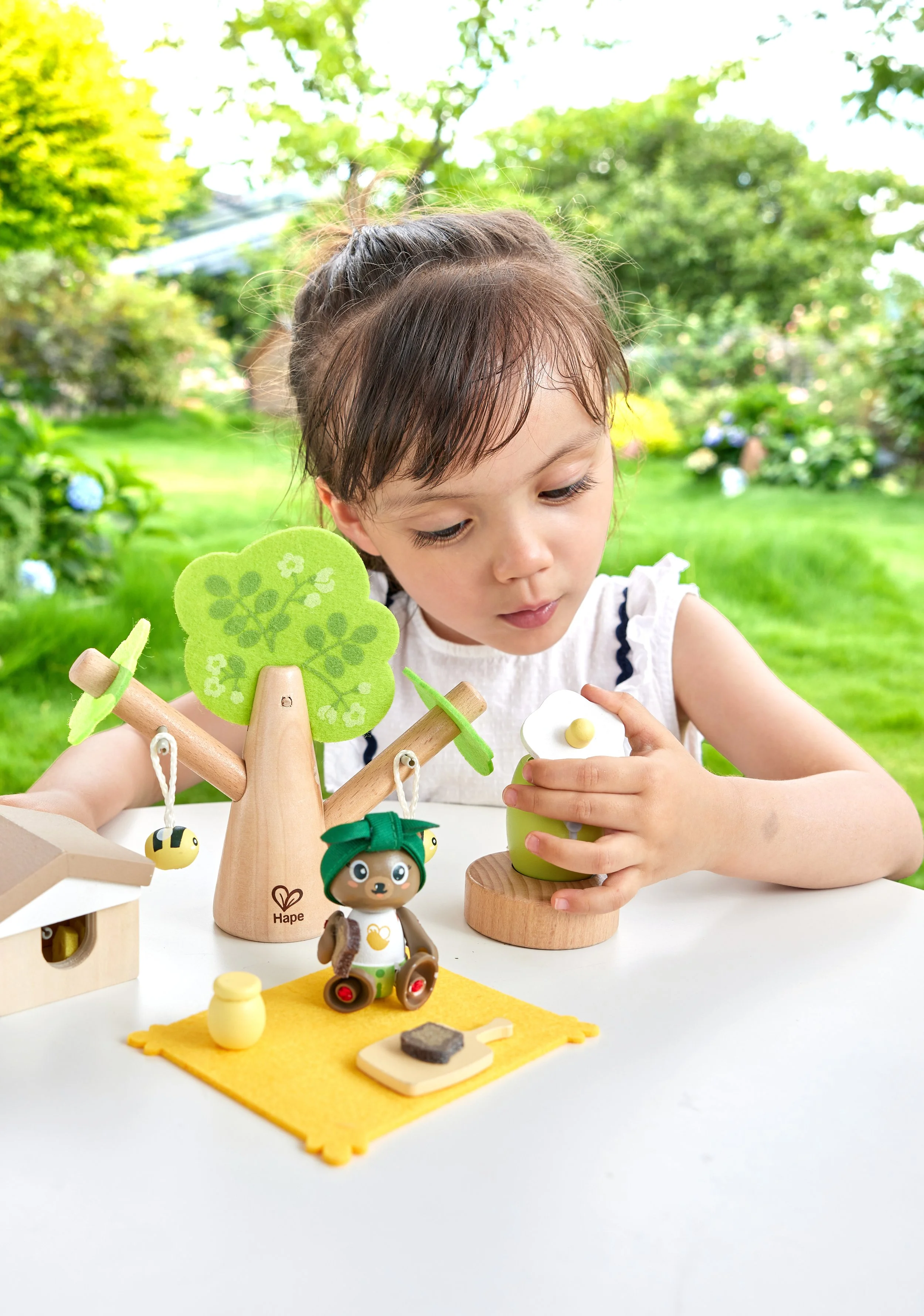 A young girl playing withGreen Planet Explorers Honey Bees Picnic by Hape.