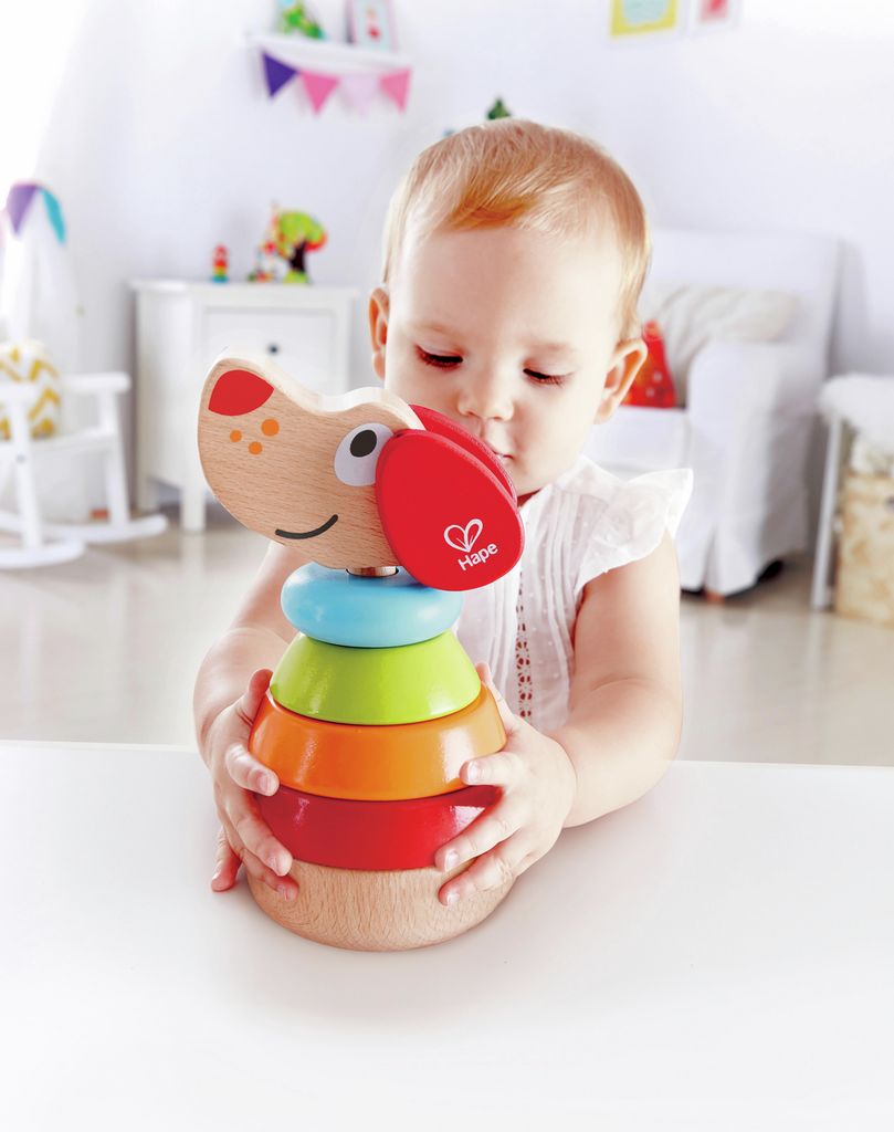 A young child playing with a wooden stacking toy Pepe the dog, with colorful rings stacked in order. Developed by Hape.