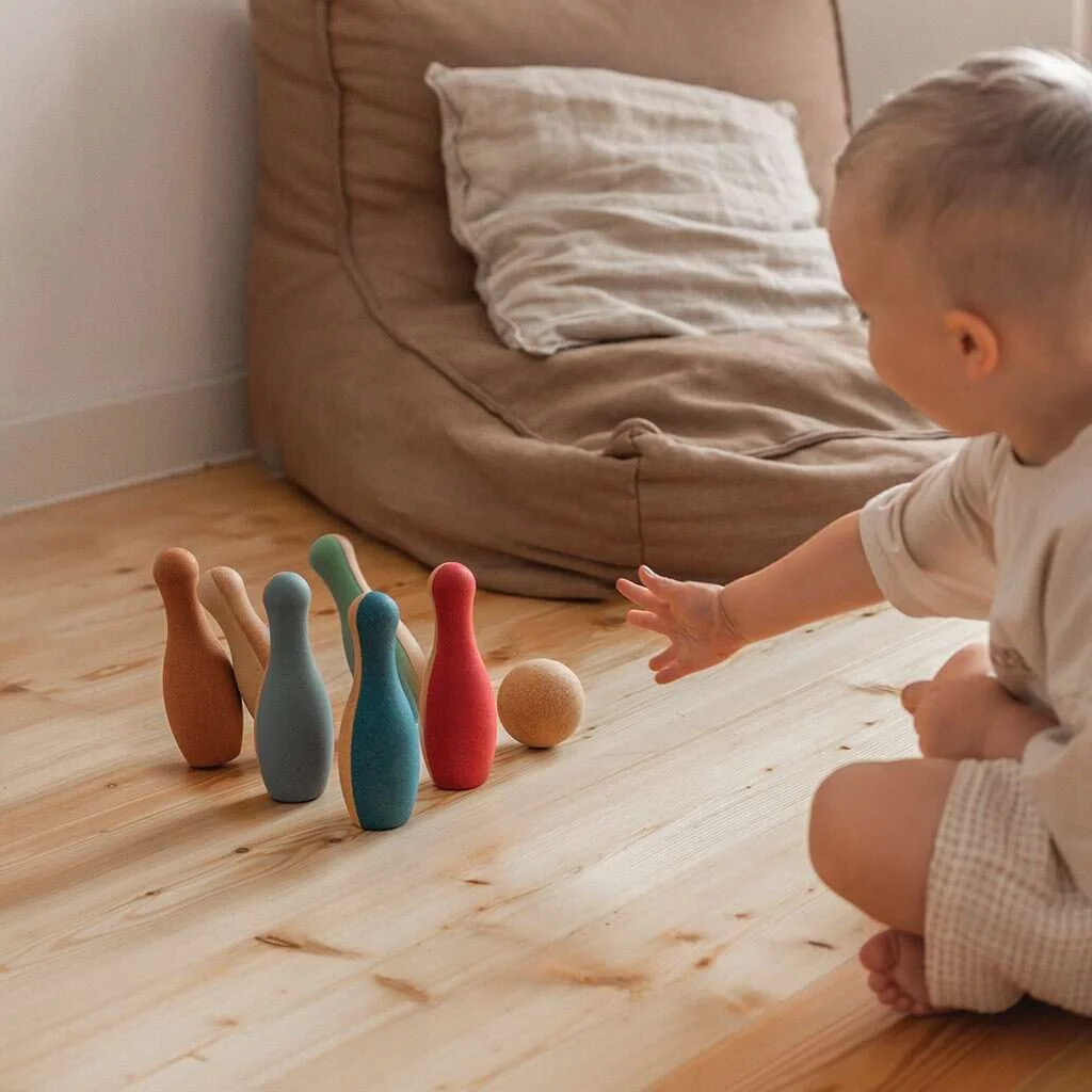 A child throws a cork ball at falling cork pins on a wooden floor. By Korko.