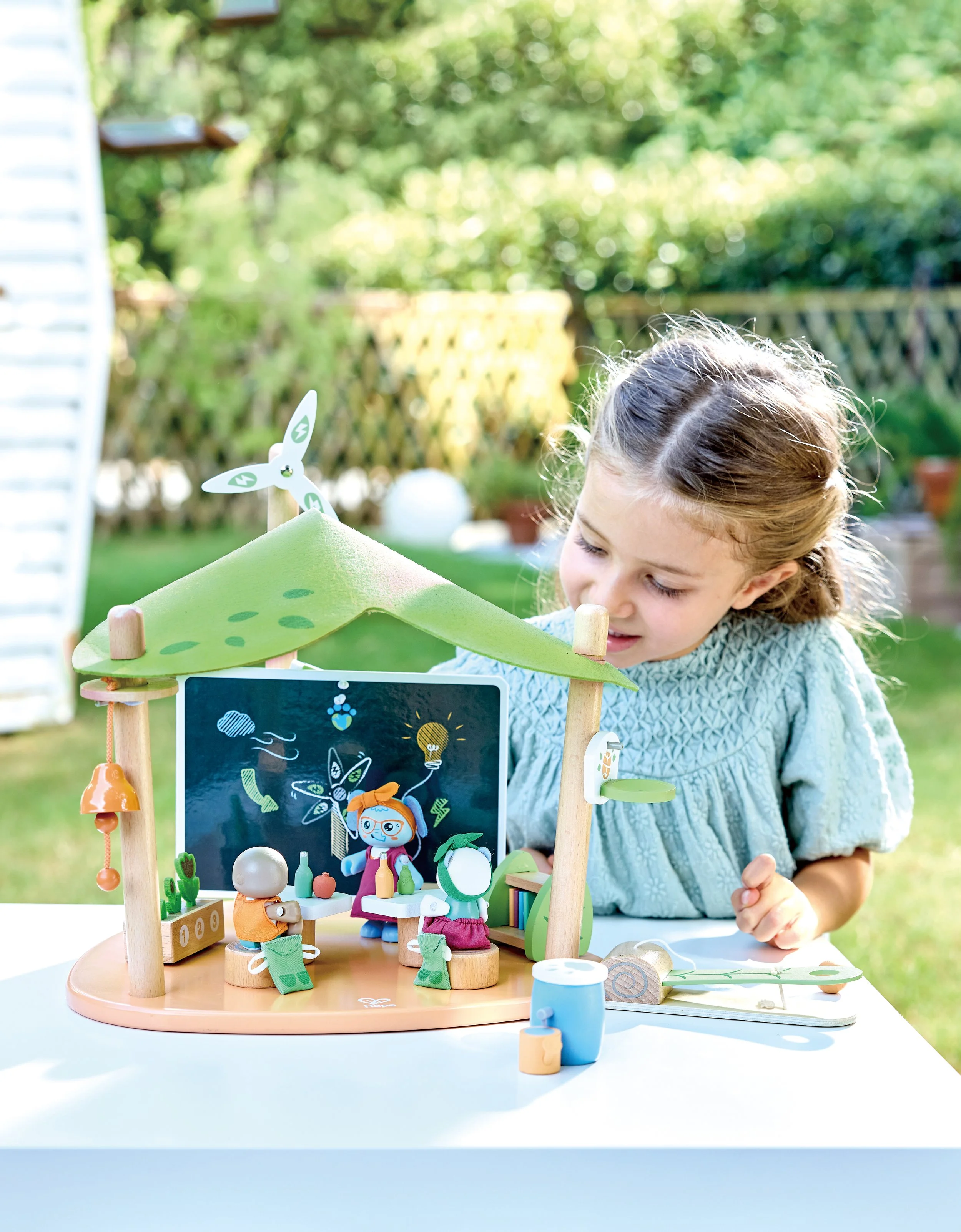 A young girl with Green Planet Explorers Green School playset by Hape.