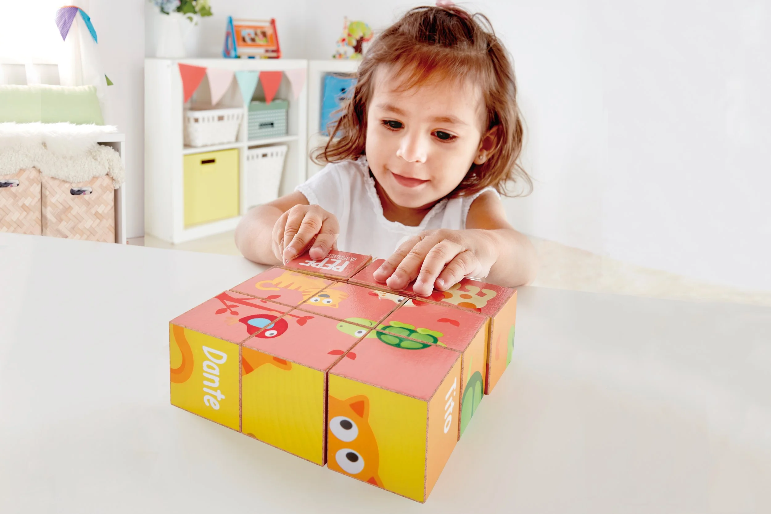A young girl with brown hair playing with a colorful educational wooden puzzle on a white table in a bright room. Developed by Hape.