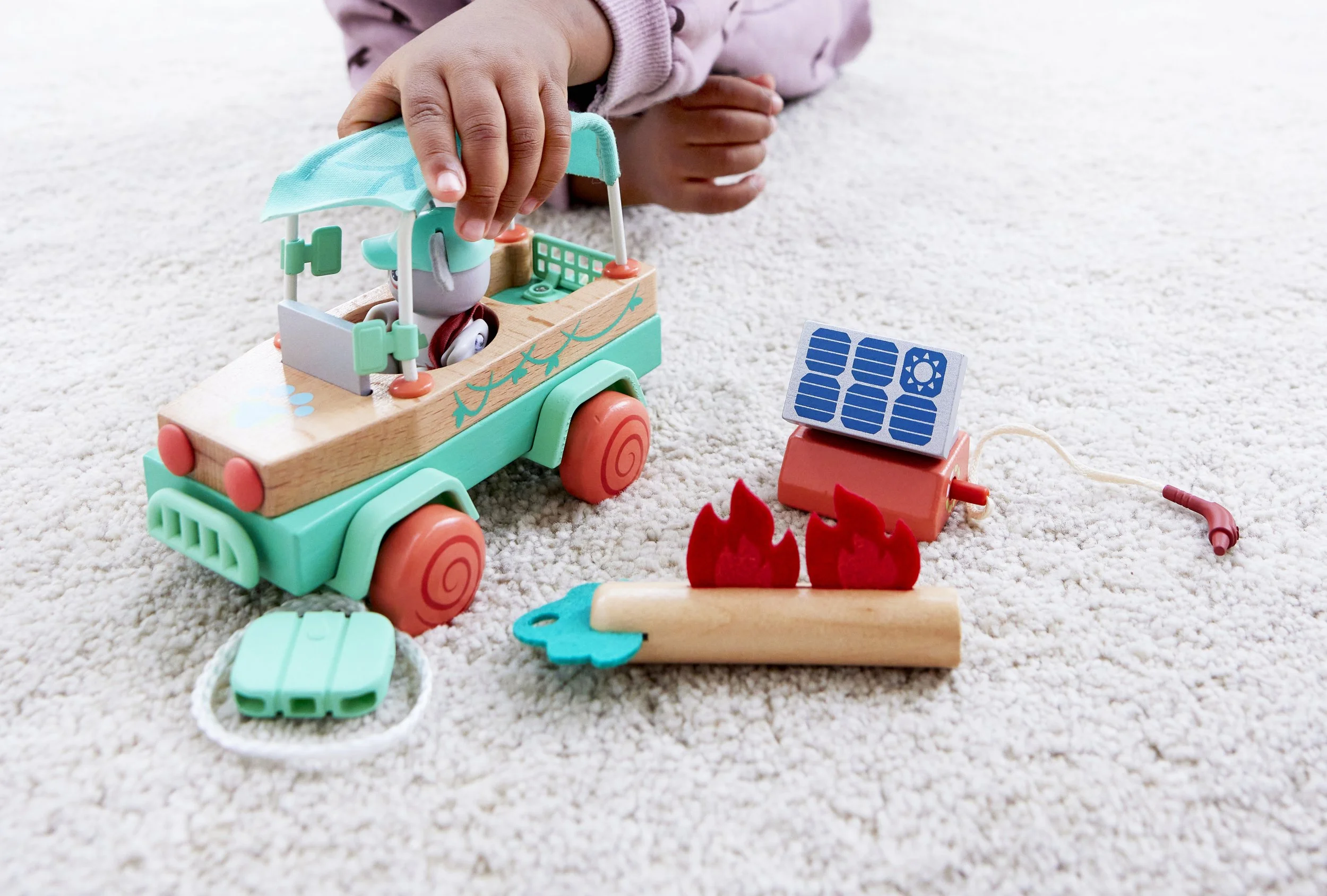 Child playing with Green Planet Explorers Solar Offroad Adventures by Hape. Miniature toy offroad car, solar panel, and firefighter accessories.