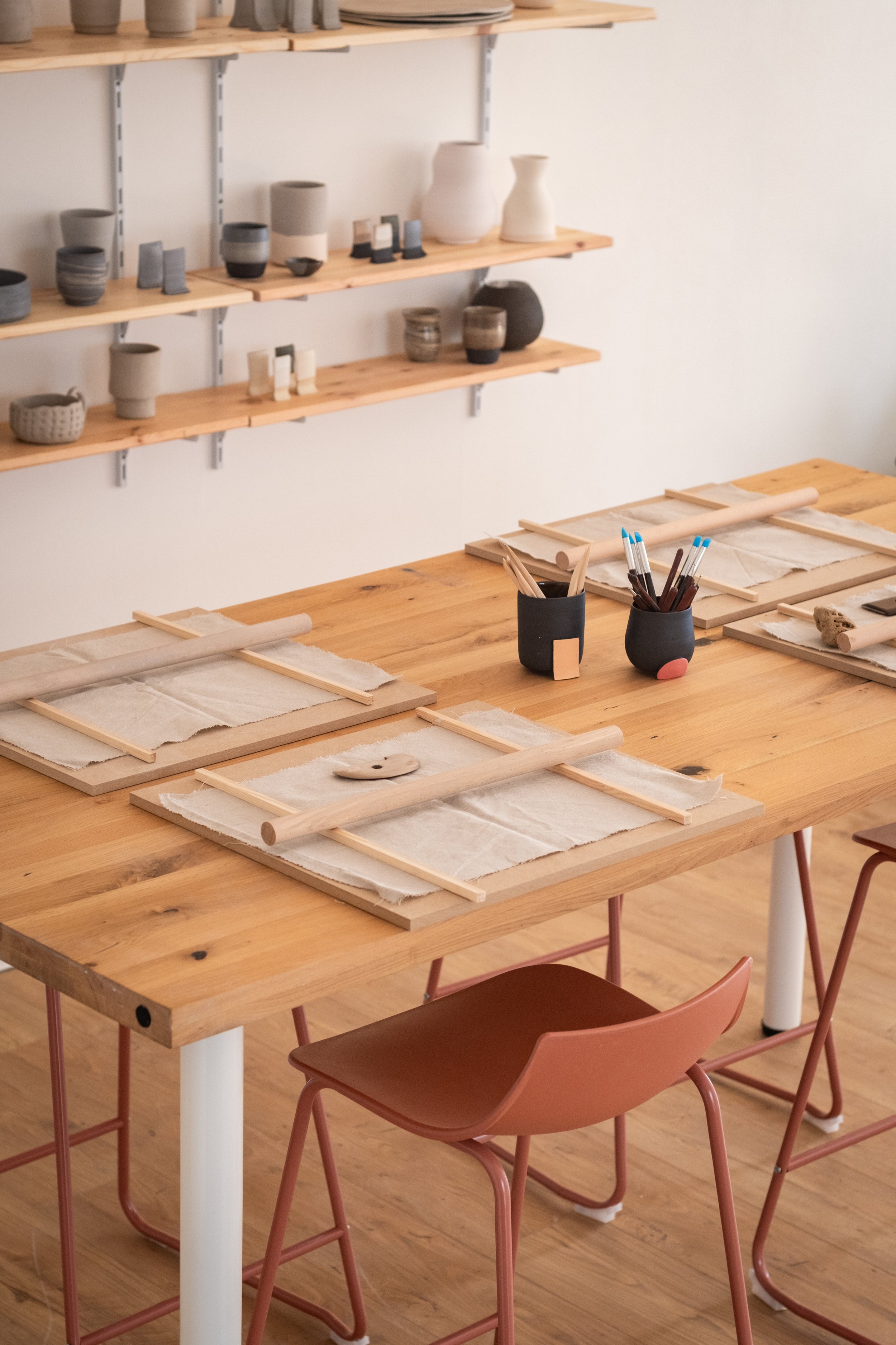 Offenes Atelier für Handarbeit. Auf dem Tisch befindet sich eine Einrichtung, in der die Studiomitglieder mit verschiedenen Werkzeugen arbeiten können, um Keramikstücke herzustellen.
