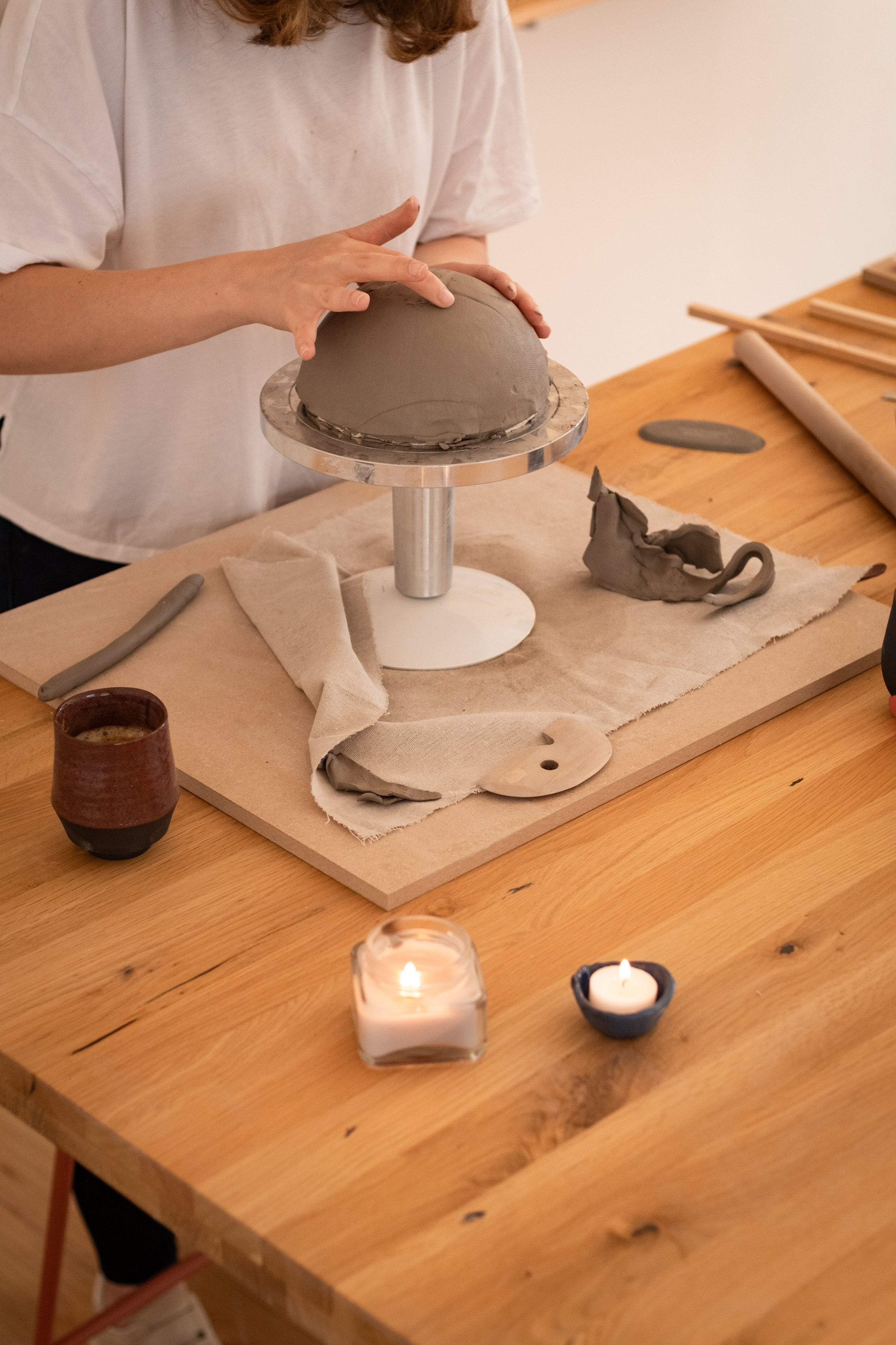 ein teilnehmer des workshops arbeitet an der herstellung einer schale in handbautechnik. die umgebung ist gemütlich und entspannt.