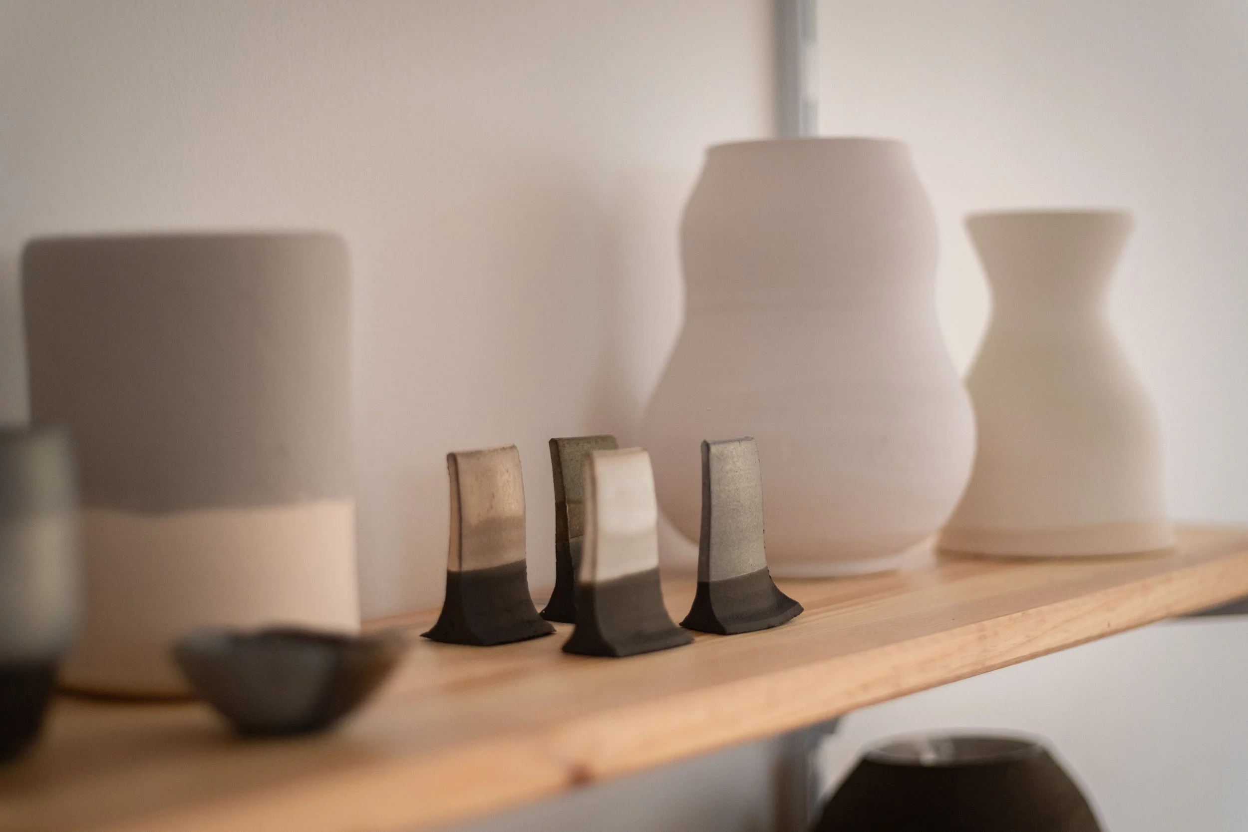 Ceramic vases and small sculptural objects displayed on a wooden shelf.