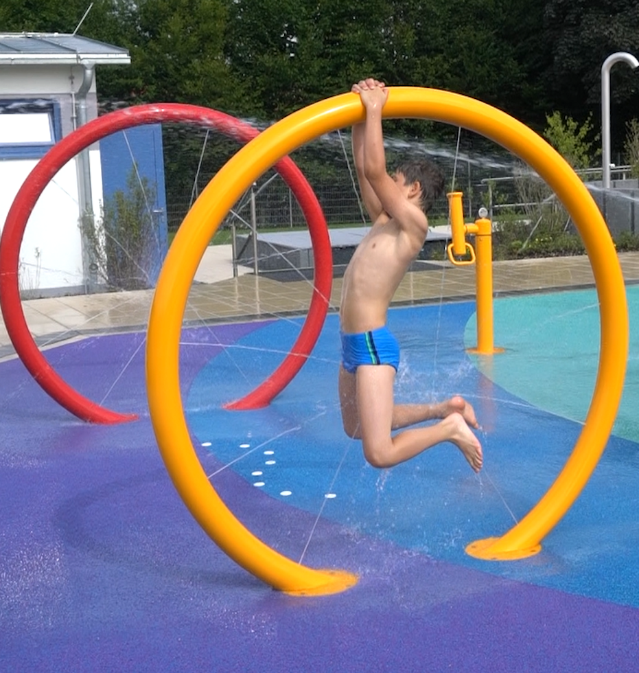 AQUANELLA – the colorful round water fountain with a delicate curtain of water, where a child is playing