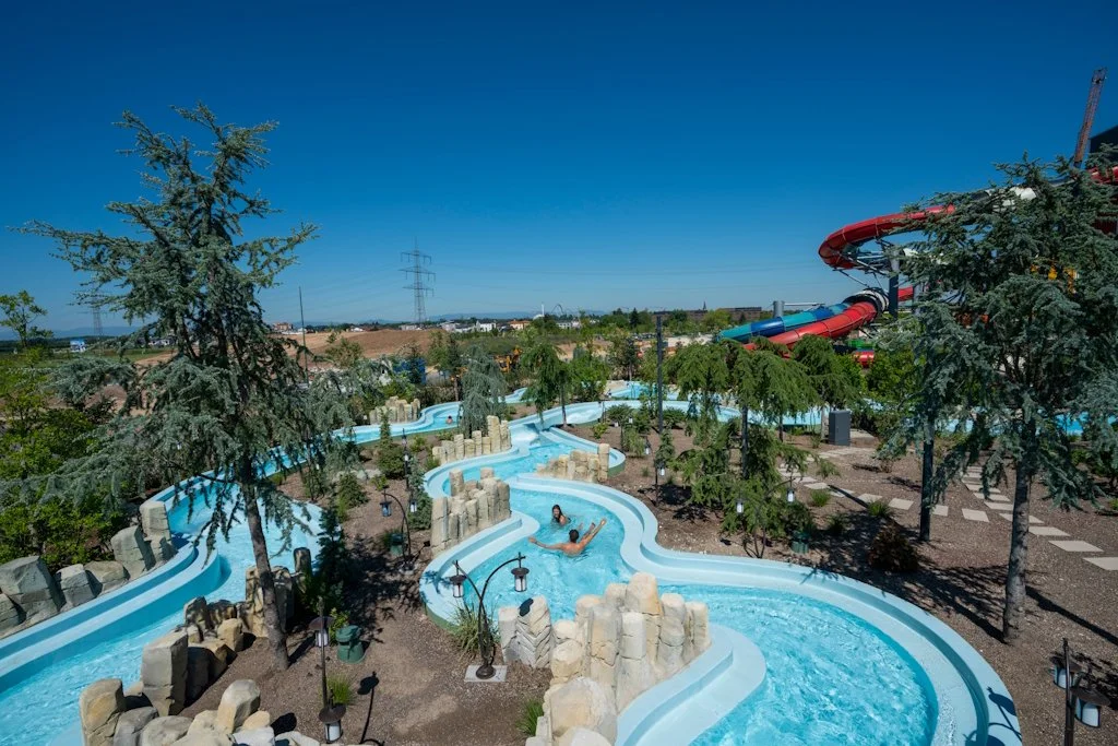View of the Rulantica Water Park featuring the Wild River attraction by API WATER FUN, surrounded by trees, with two people in the water