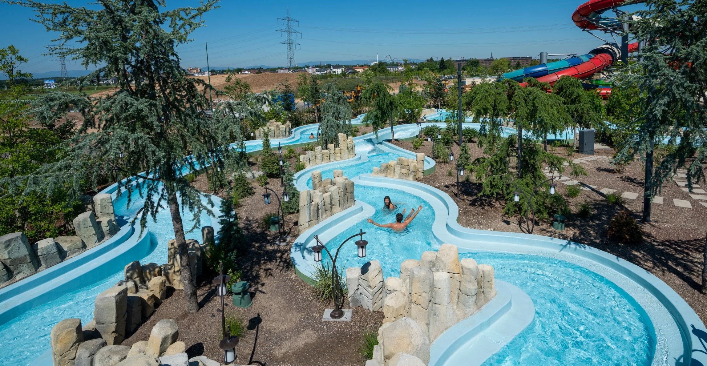 View of the Rulantica Water Park featuring the Wild River attraction by API WATER FUN, surrounded by trees, with two people in the water