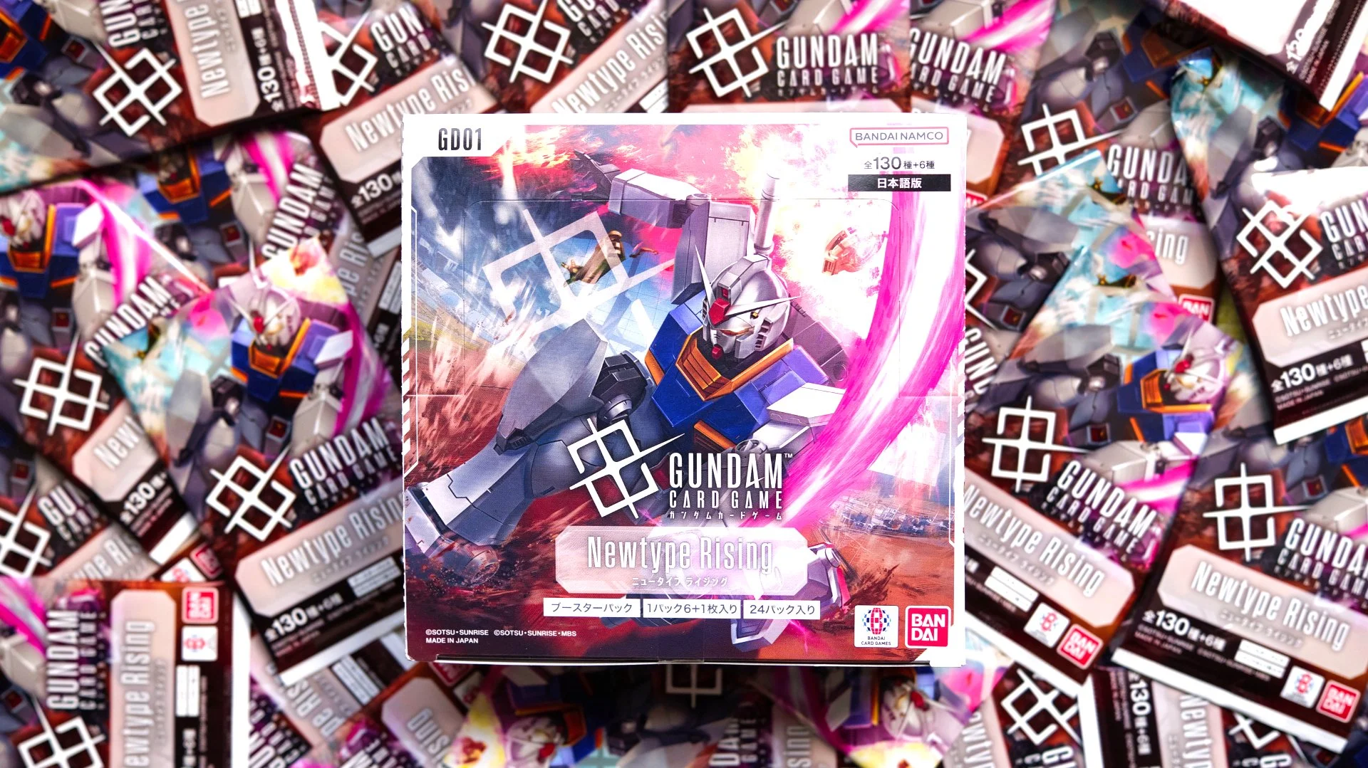 Gundam Card Game Newtype Rising Box, sitting on top of a spread of individual packs.