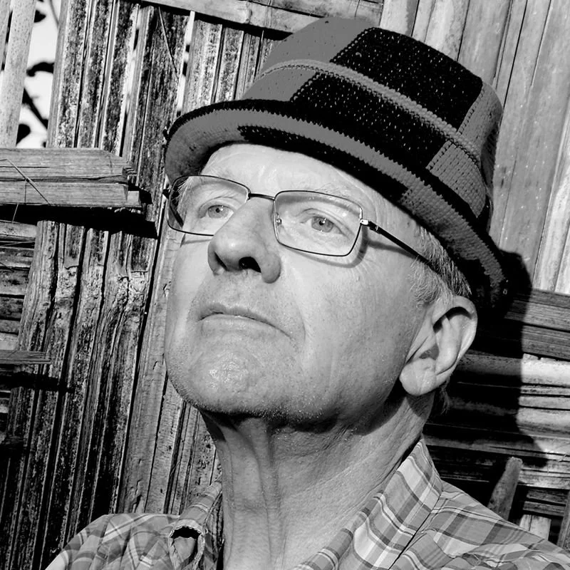 A black and white photo of a man with glasses wearing a hat.