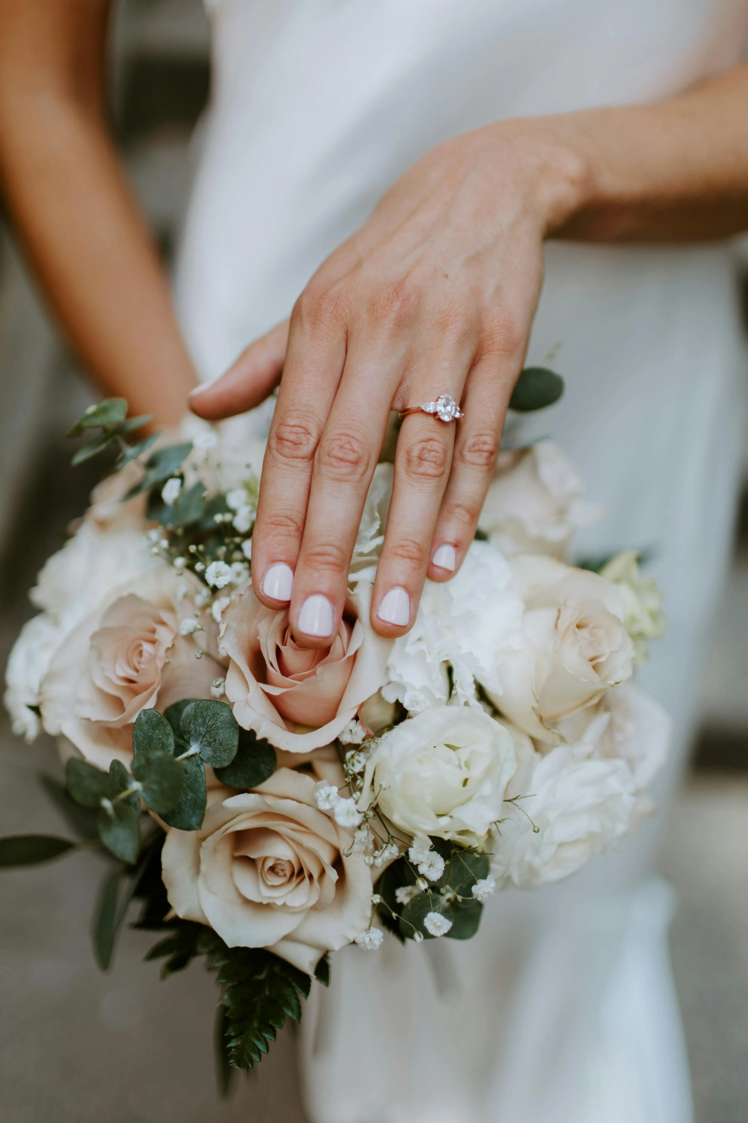 bride showing her wedding ring against white and pink wedding flowers