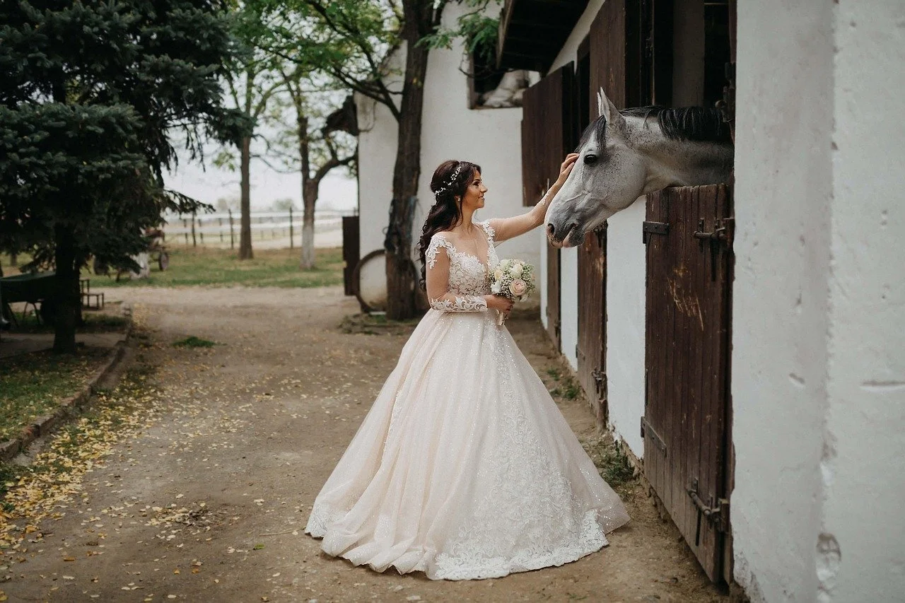 bride touching horses face in the stables