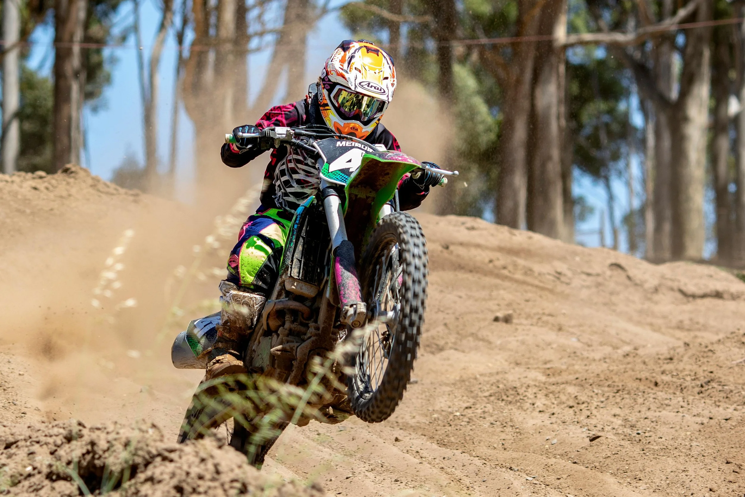 motocross rider coming up over the hill on a dirt track
