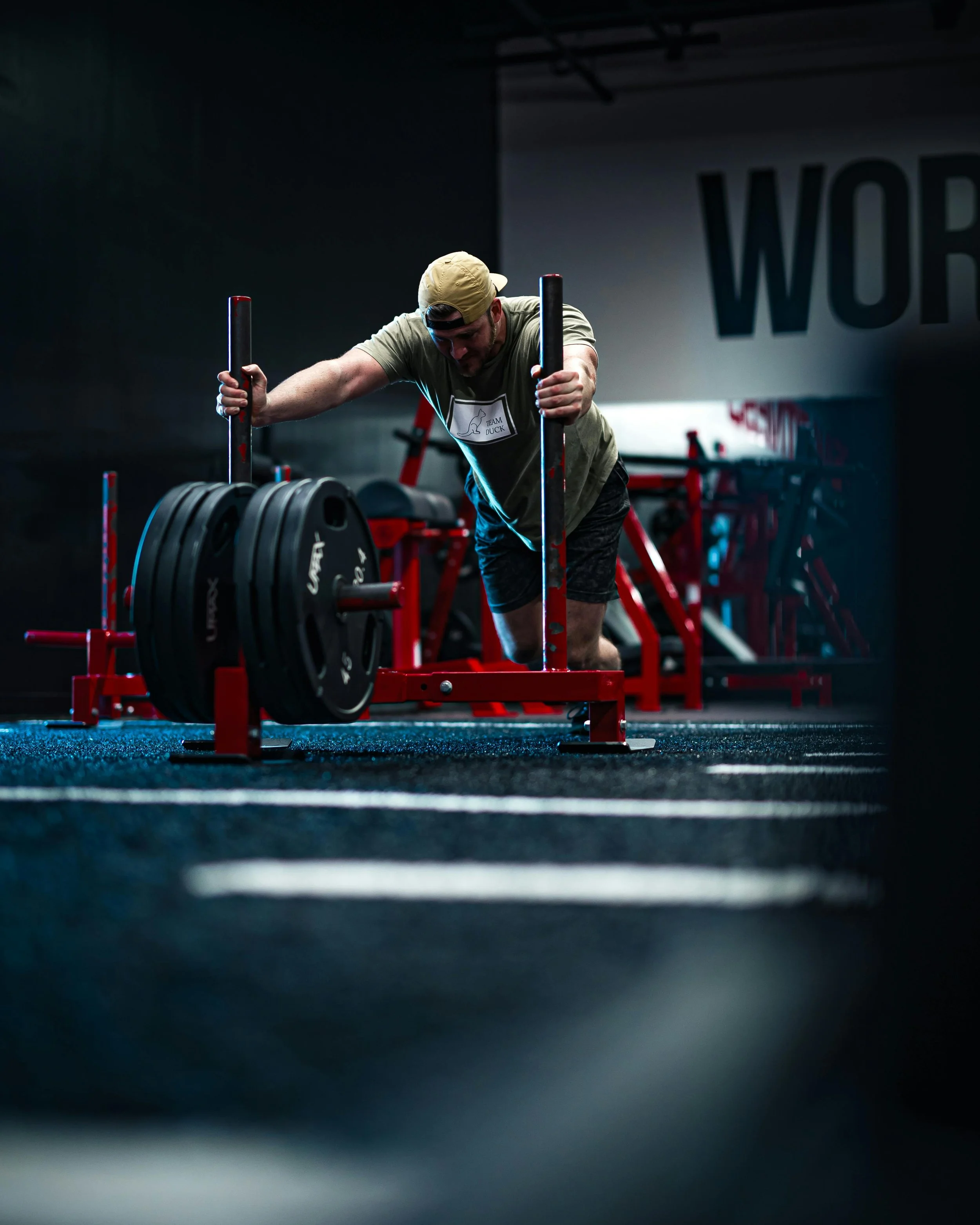 dramatic gym workout scene with man pushing weighted sled