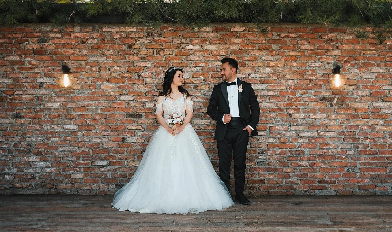 bride and groom together holding hands against a wall