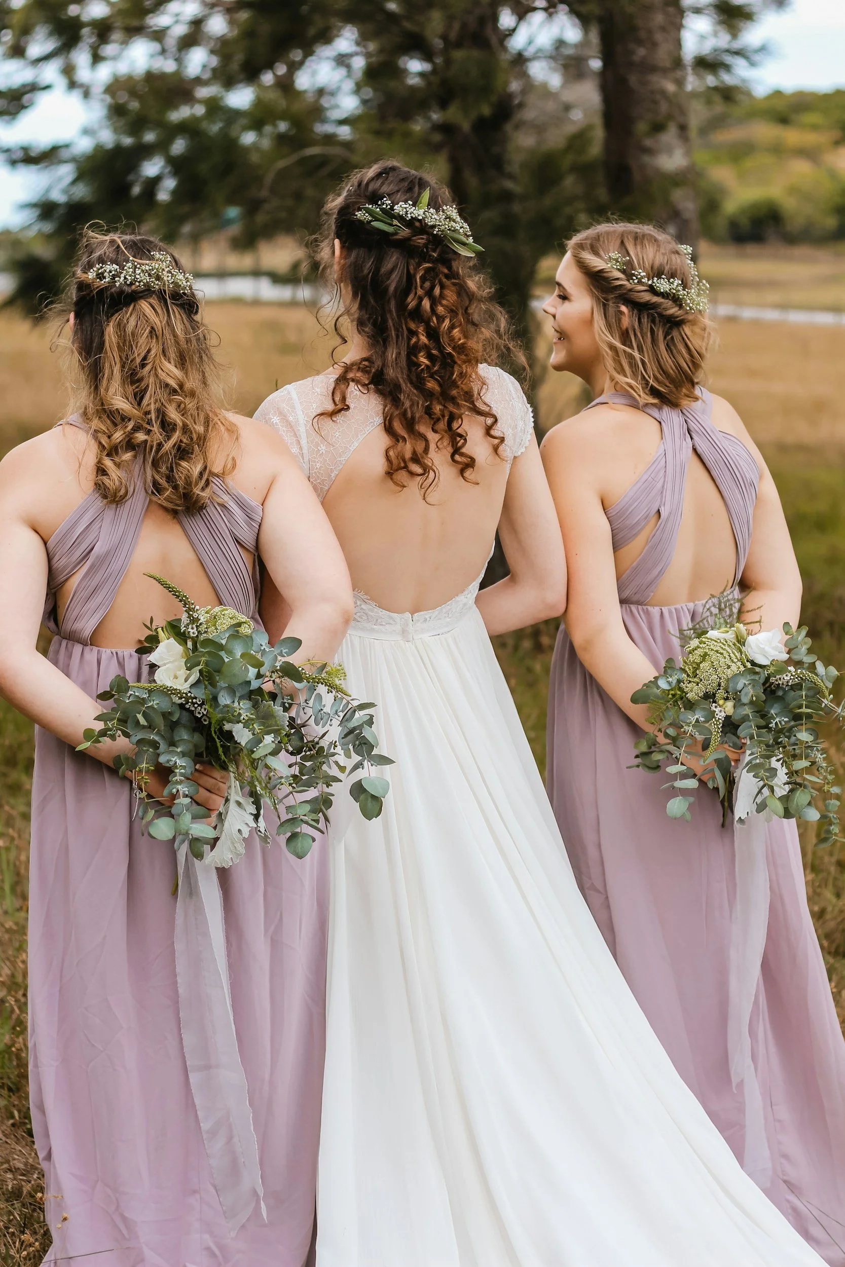 bride walking away with her two bridesmaids and flowers