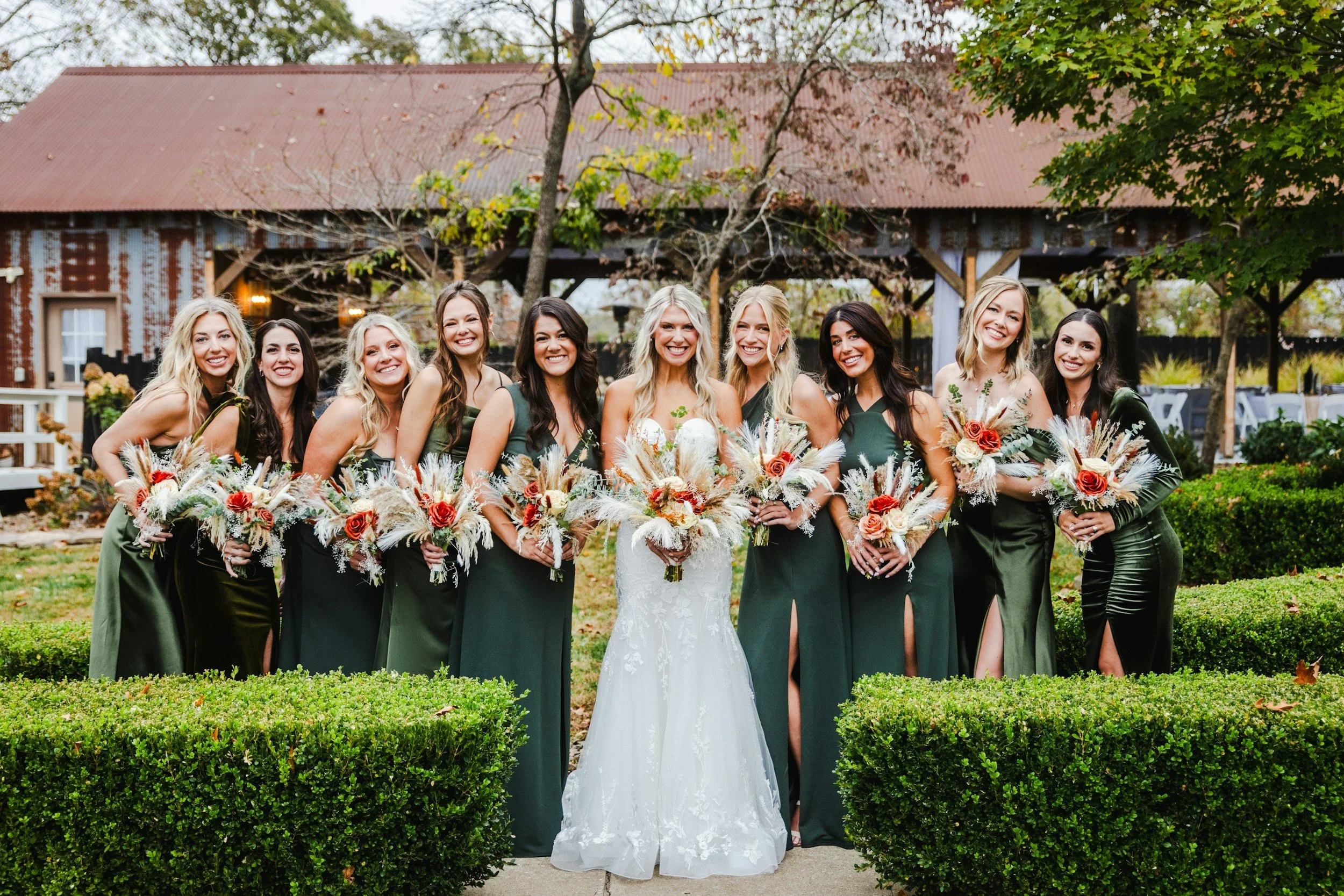 bride with her bridesmaids stood together holding flowers
