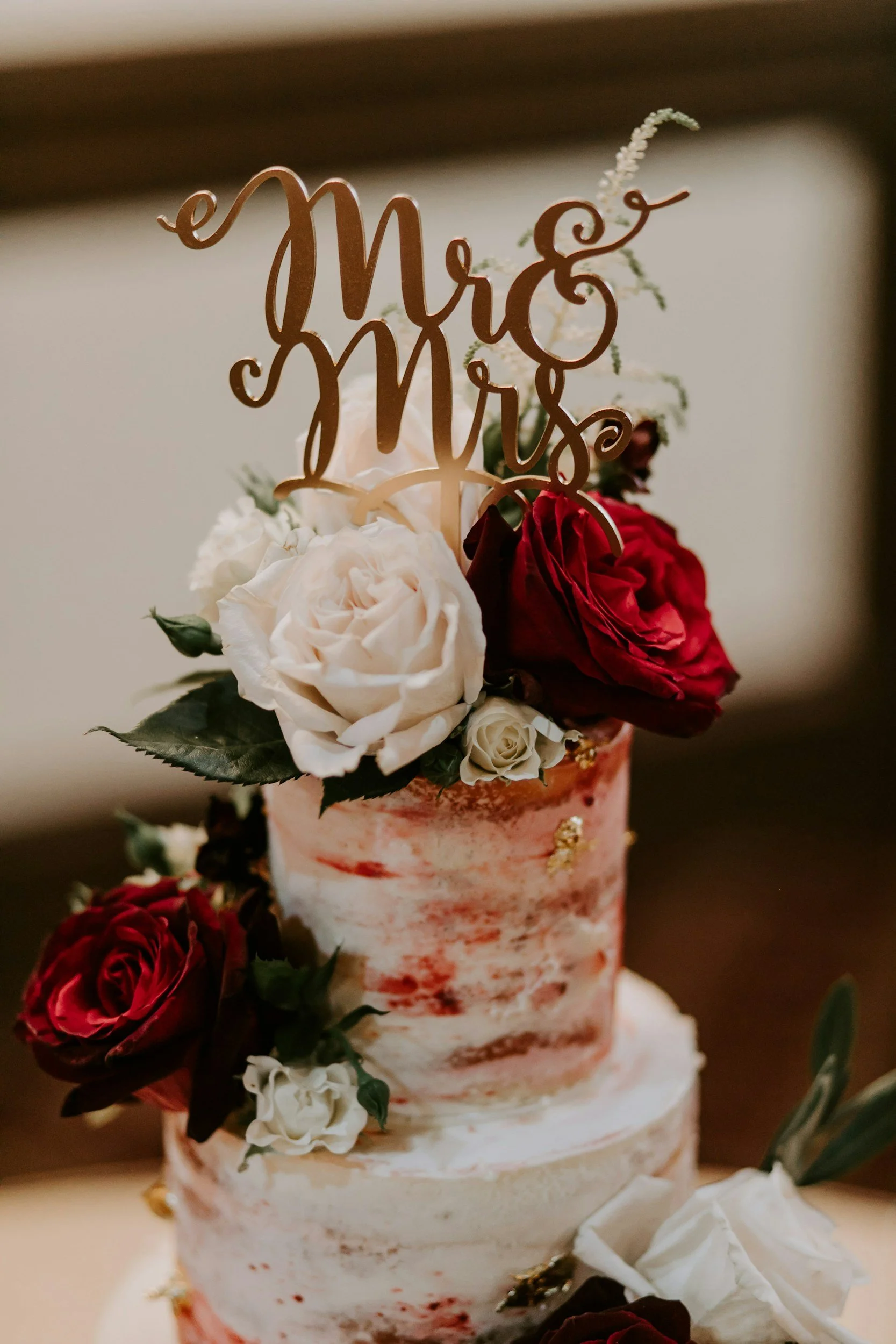 wedding cake with white and red flowers with mr and mrs topper