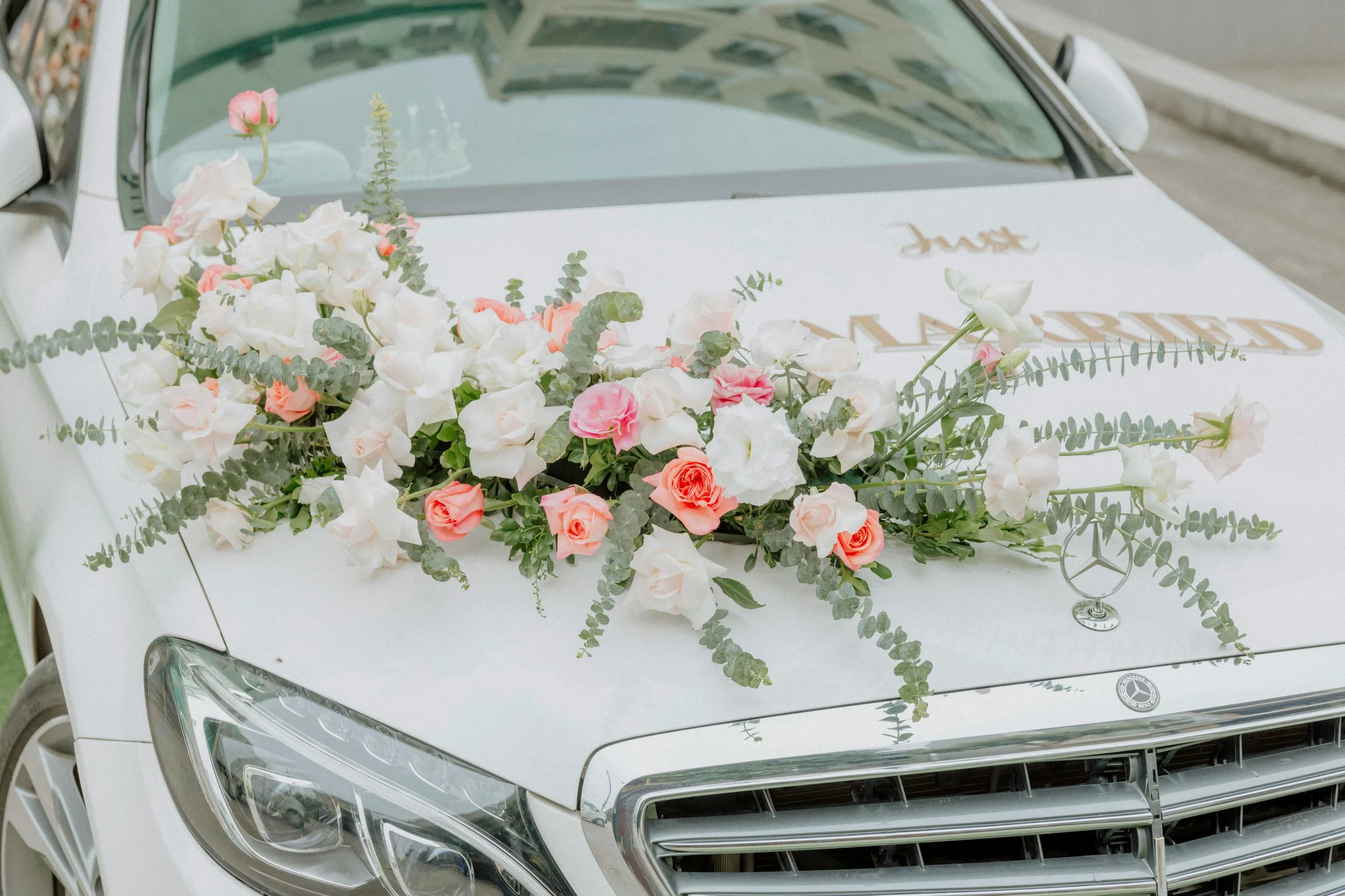 pink and white wedding flowers on white wedding car